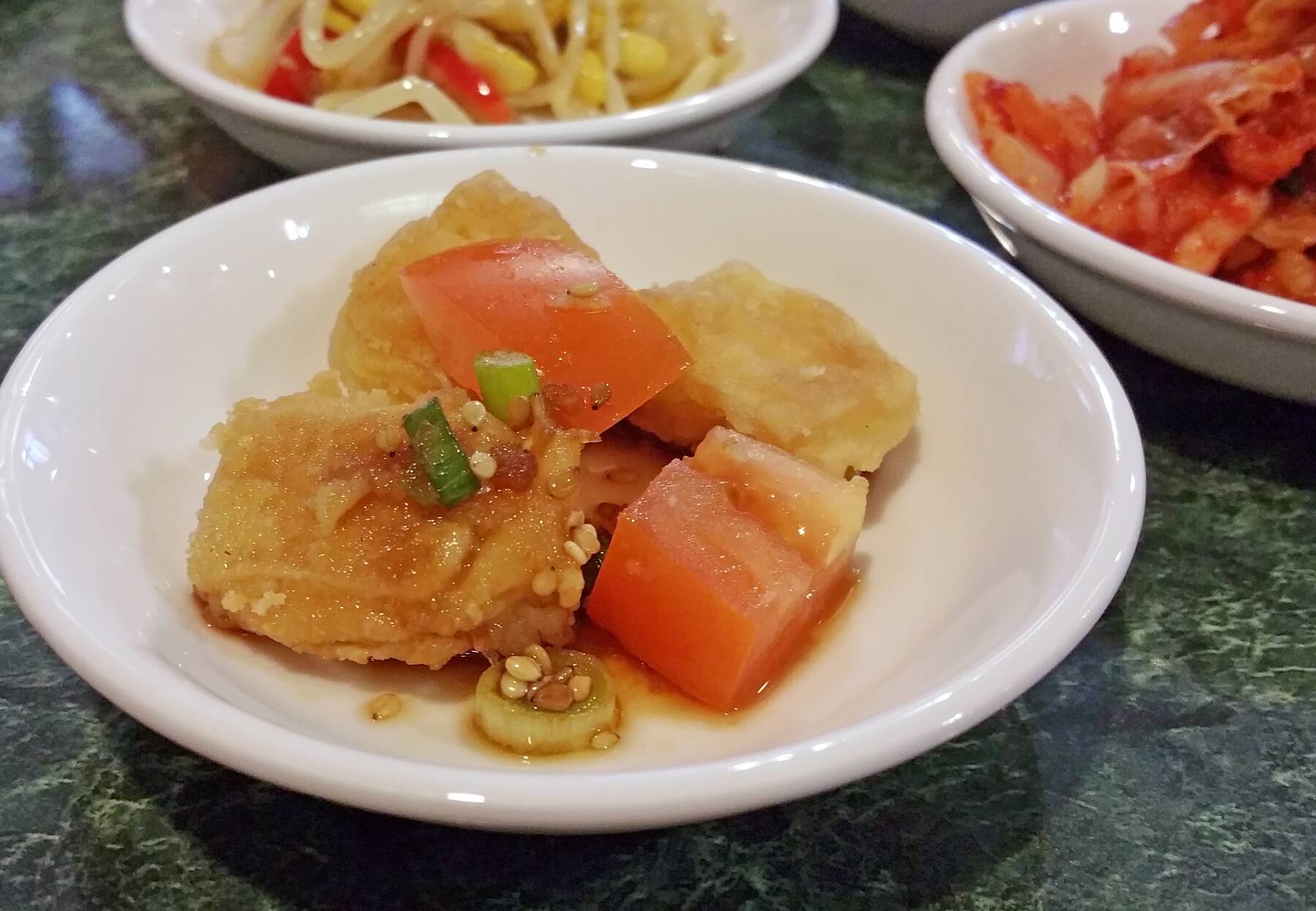 Tofu is also a traditional side dish, along with mung bean sprouts and kimchi (pictured in the background). Tofu is also a traditional side dish, along with mung bean sprouts and kimchi (pictured in the background).