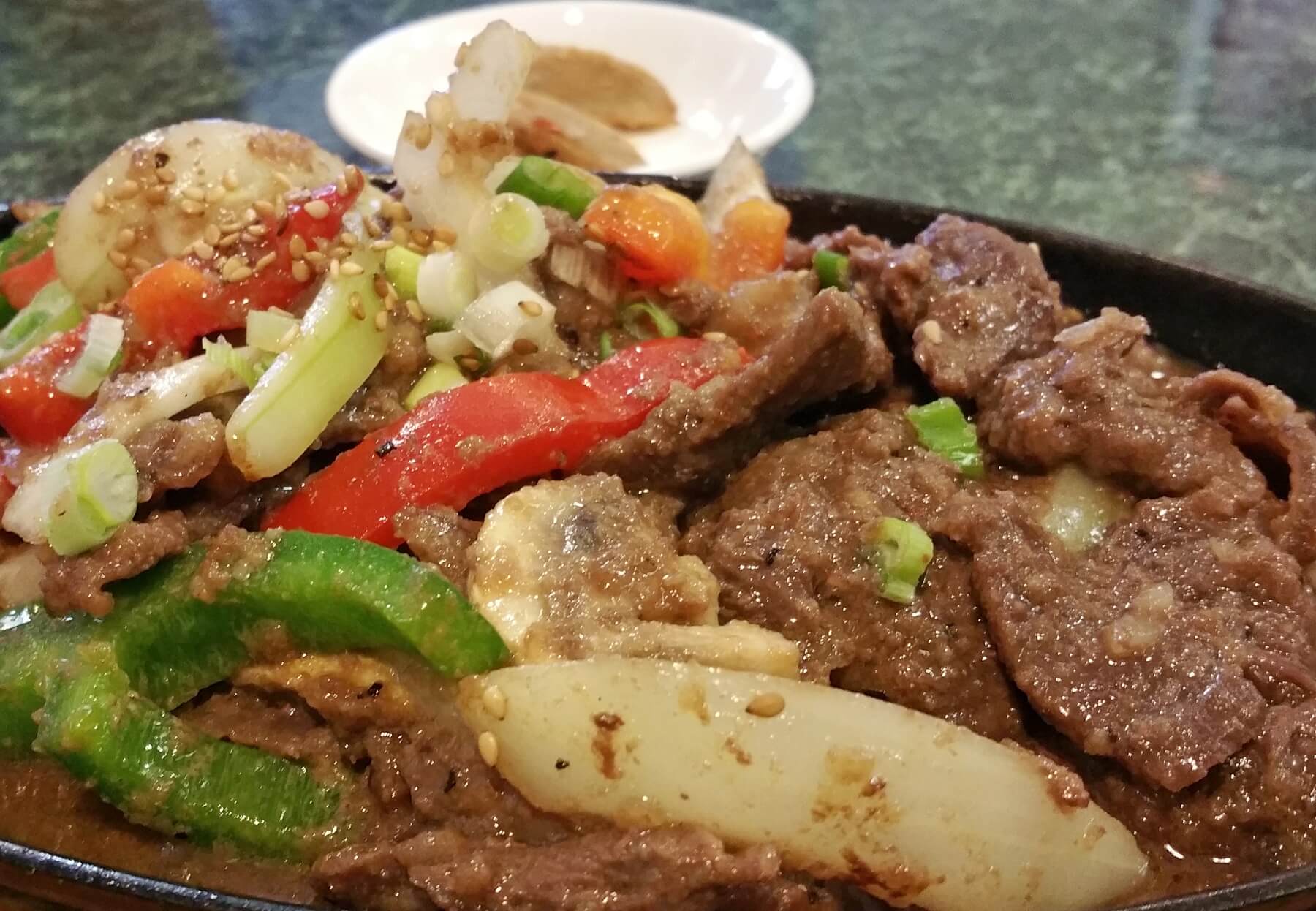 Beef Bul Go Gi is an impressively tasty marinated beef dish with sauteed peppers and onions topped with scallions and sesame seeds. Beef Bul Go Gi is an impressively tasty marinated beef dish with sauteed peppers and onions topped with scallions and sesame seeds.