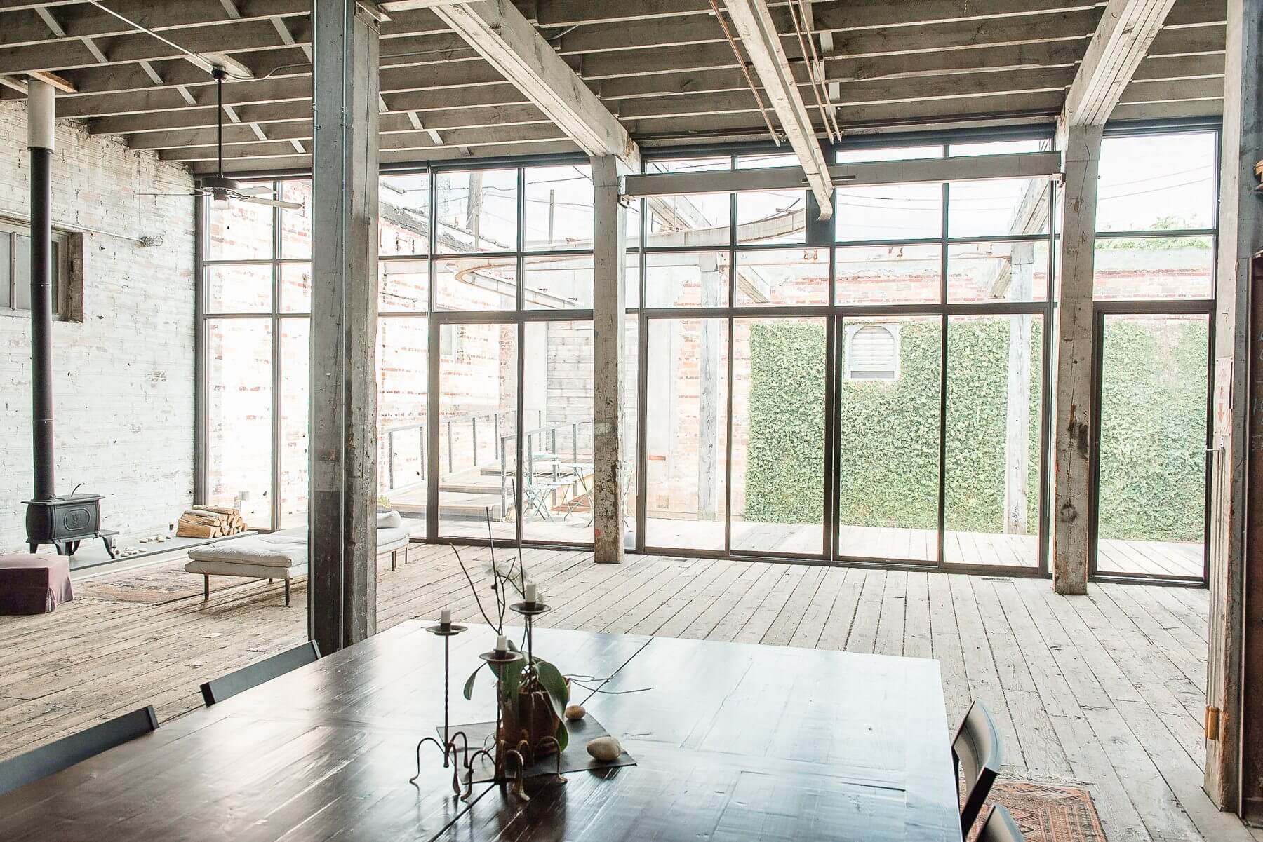 The wall of windows and doors onto Cheryl's courtyard, flooding the warm industrial space with natural light, are a signature architectural element of the home. The wall of windows and doors onto Cheryl's courtyard, flooding the warm industrial space with natural light, are a signature architectural element of the home.