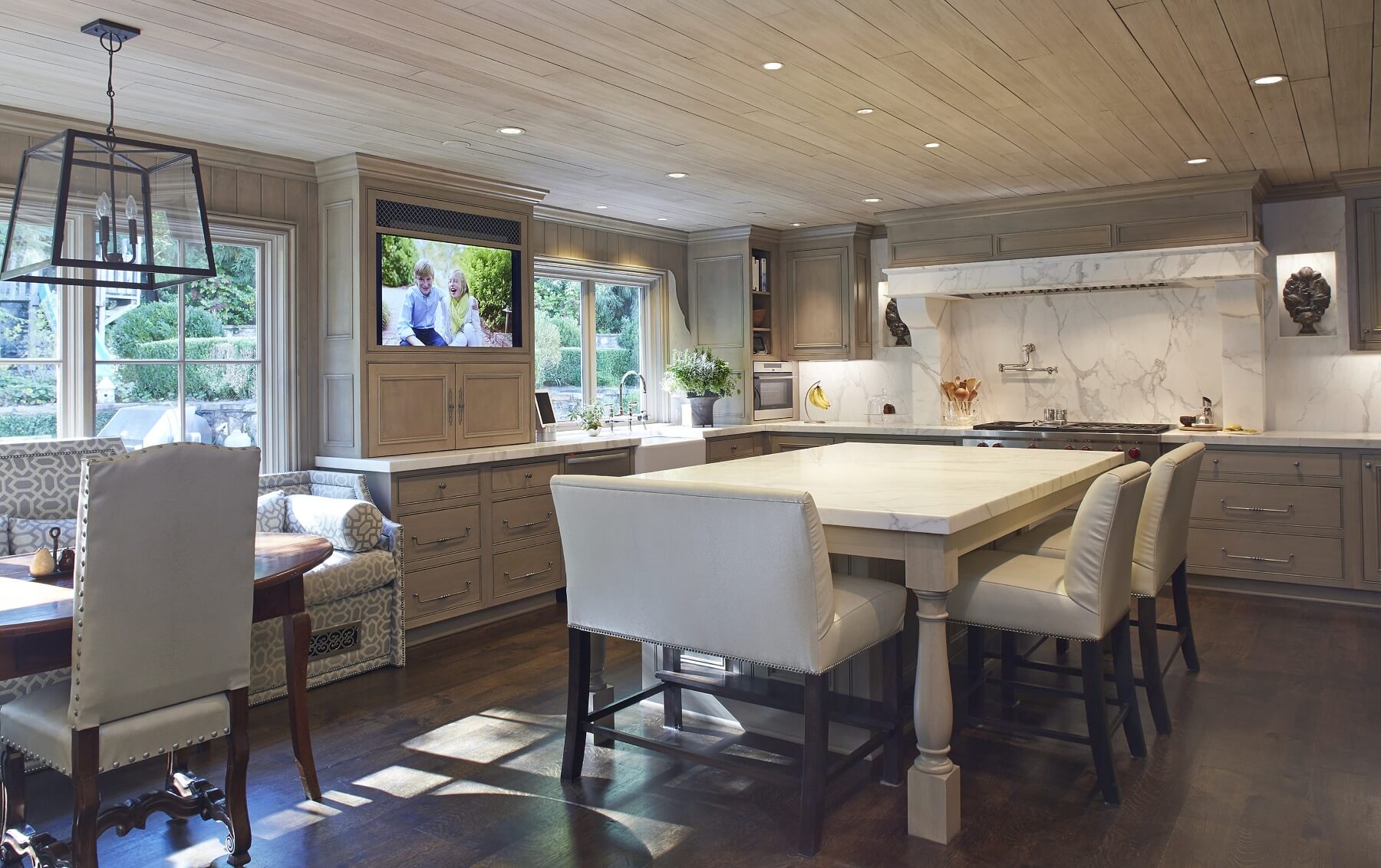 Gorgeous lighting. warm wood, sleek white marble, custom banquets and a cleverly hidden TV combine to form a kitchen we definitely want to linger in long after dinner. 