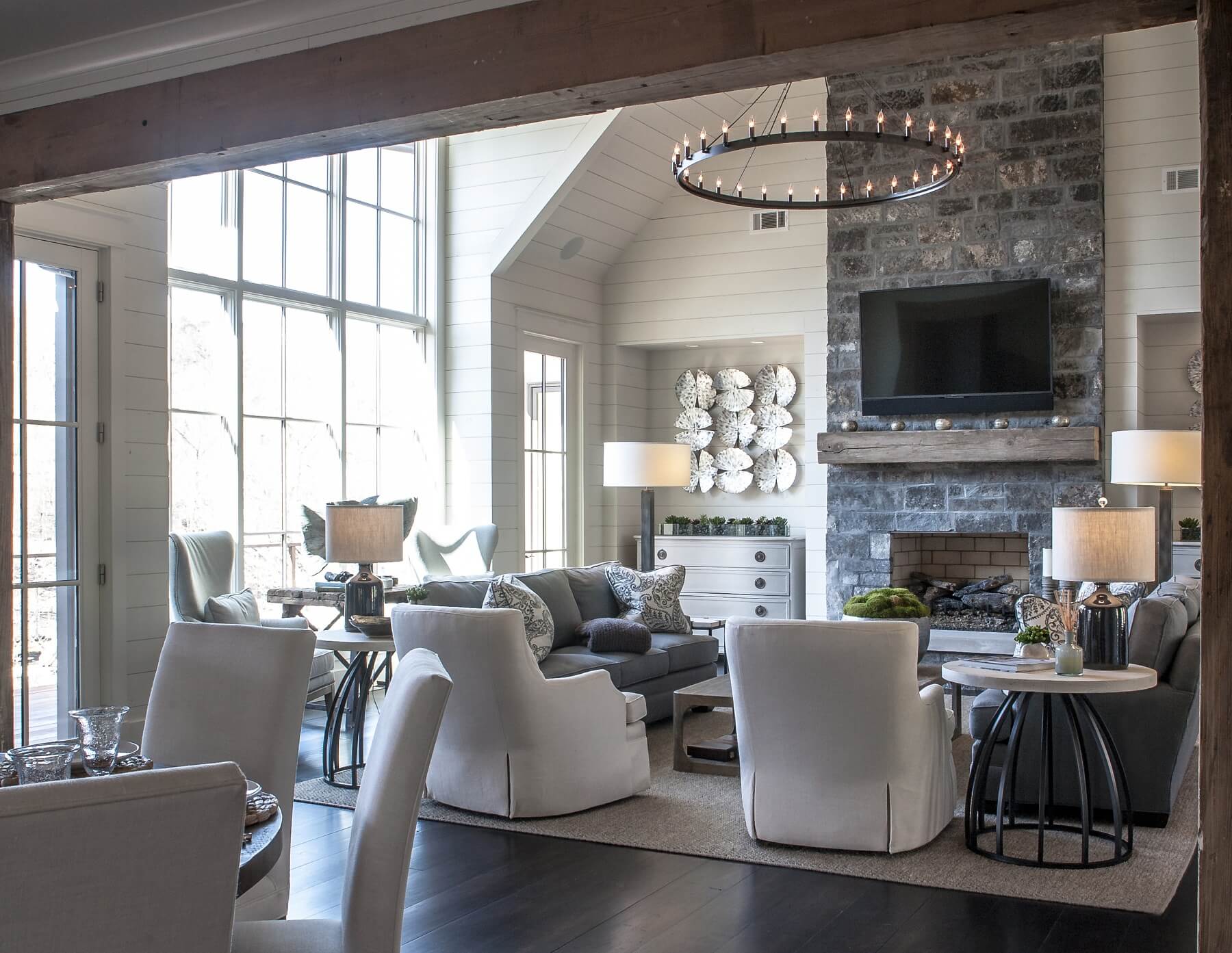 The airy living area adjoins the dining room and kitchen via wide openings framed by rustic wood beams.