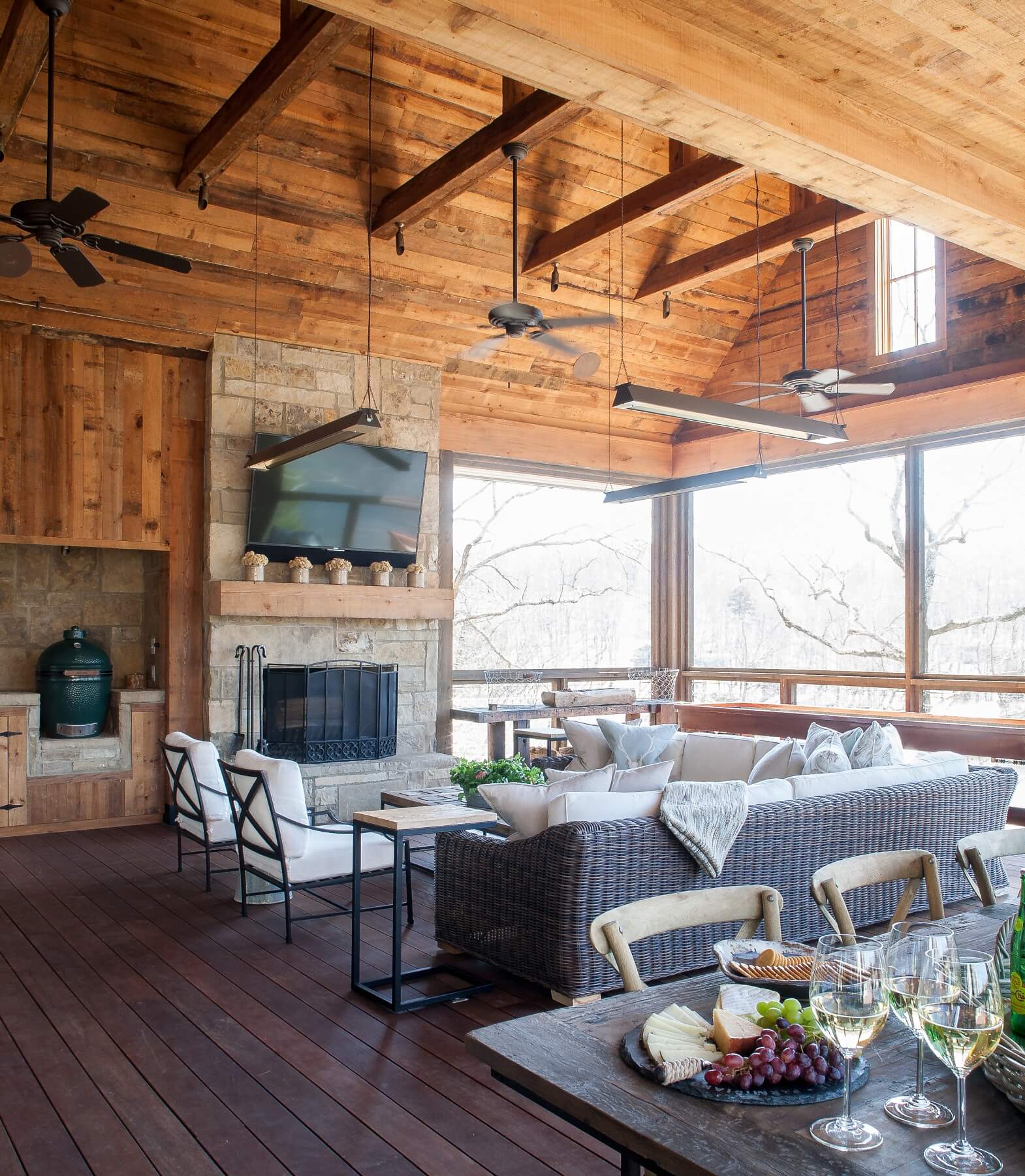 Along with the dining table, the spacious porch features an L-shaped wicker sofa and two side chairs oriented around the stone fireplace and mounted flat-screen TV, creating an ideal spot for family entertaining. 