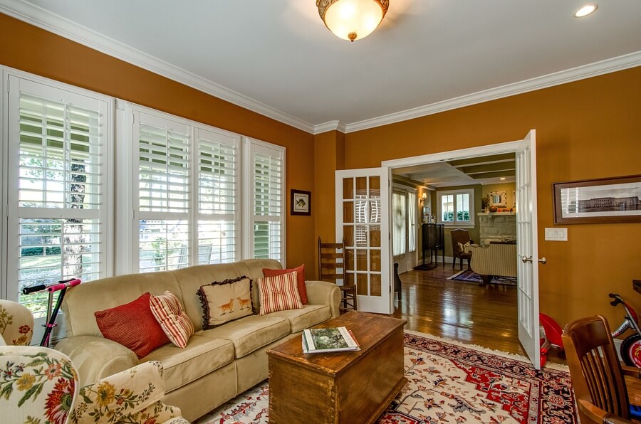 This view from inside the library looks back into the living room. We love the custom trim and plantation shutters, which add to the coziness of this room.