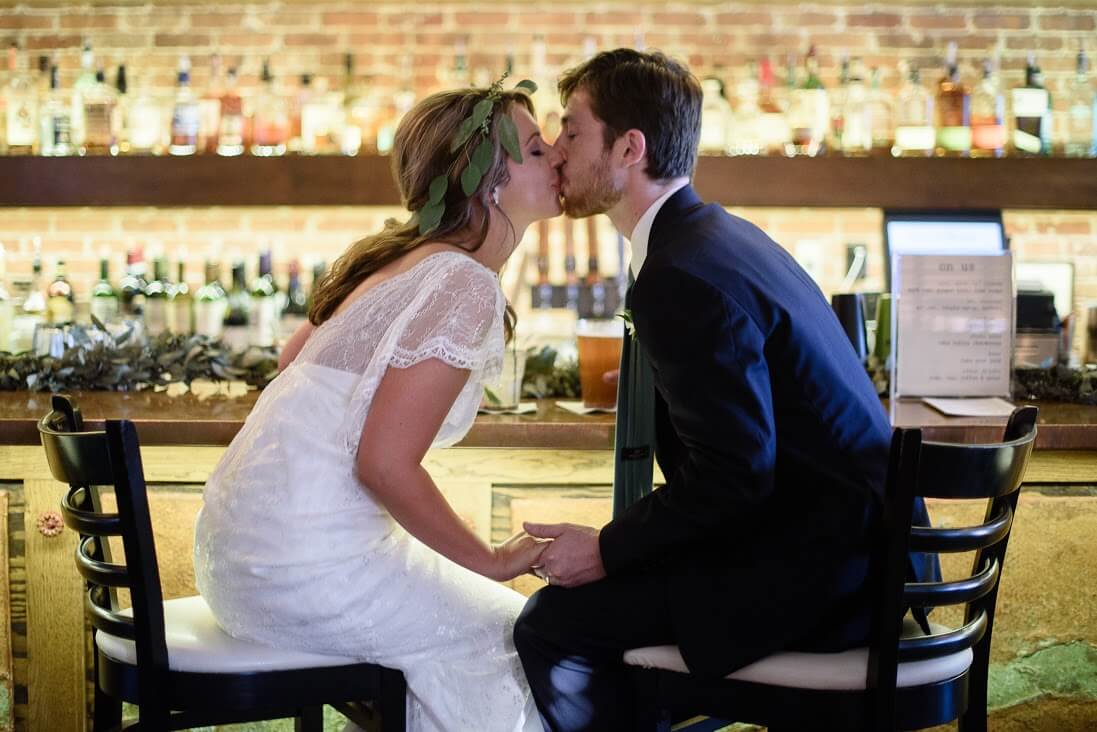 The Bride and Groom steal a kiss at the indoor bar.