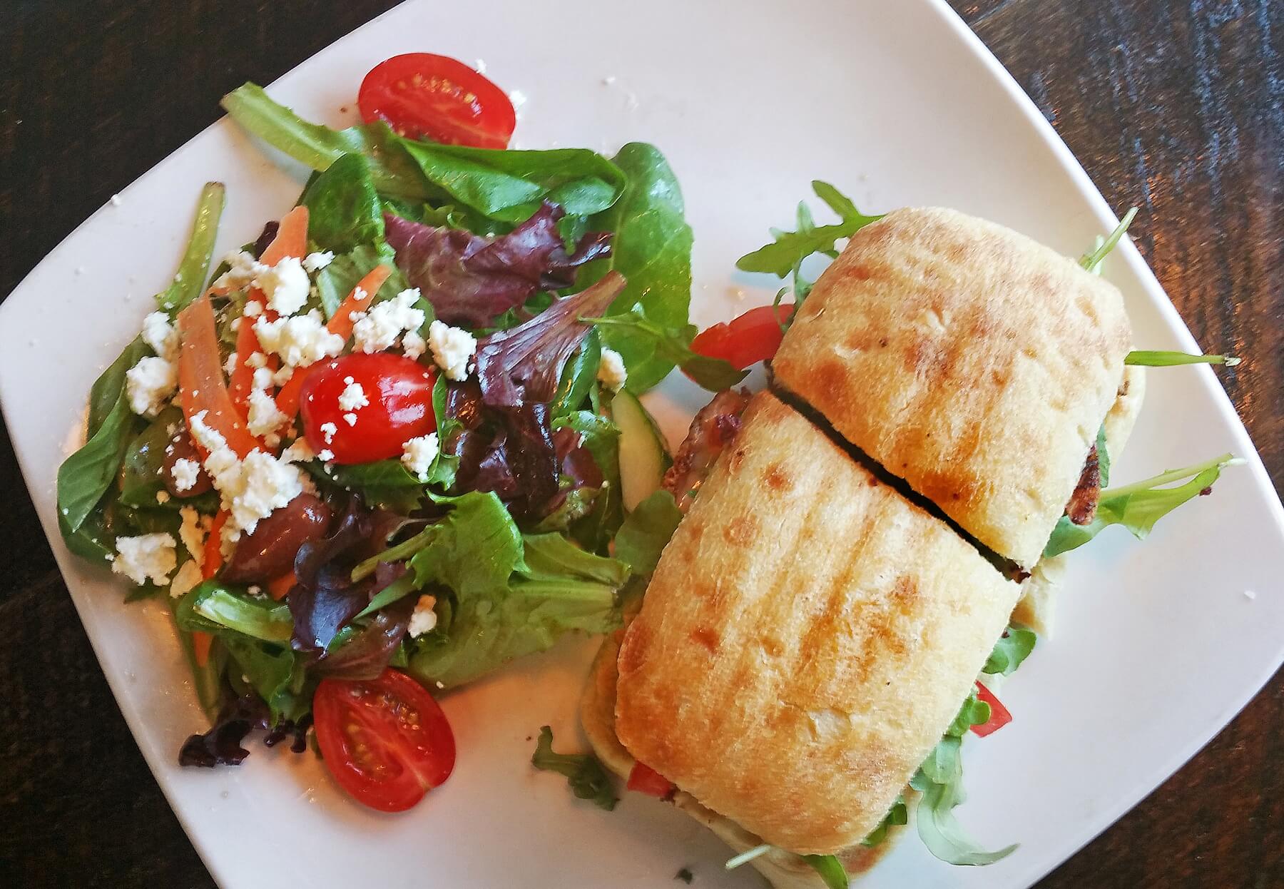 The Tuscan grilled chicken sandwich is served with pesto mayo, provolone, olive tapenade, arugula and tomato on a ciabatta bun with a side of Greek salad.