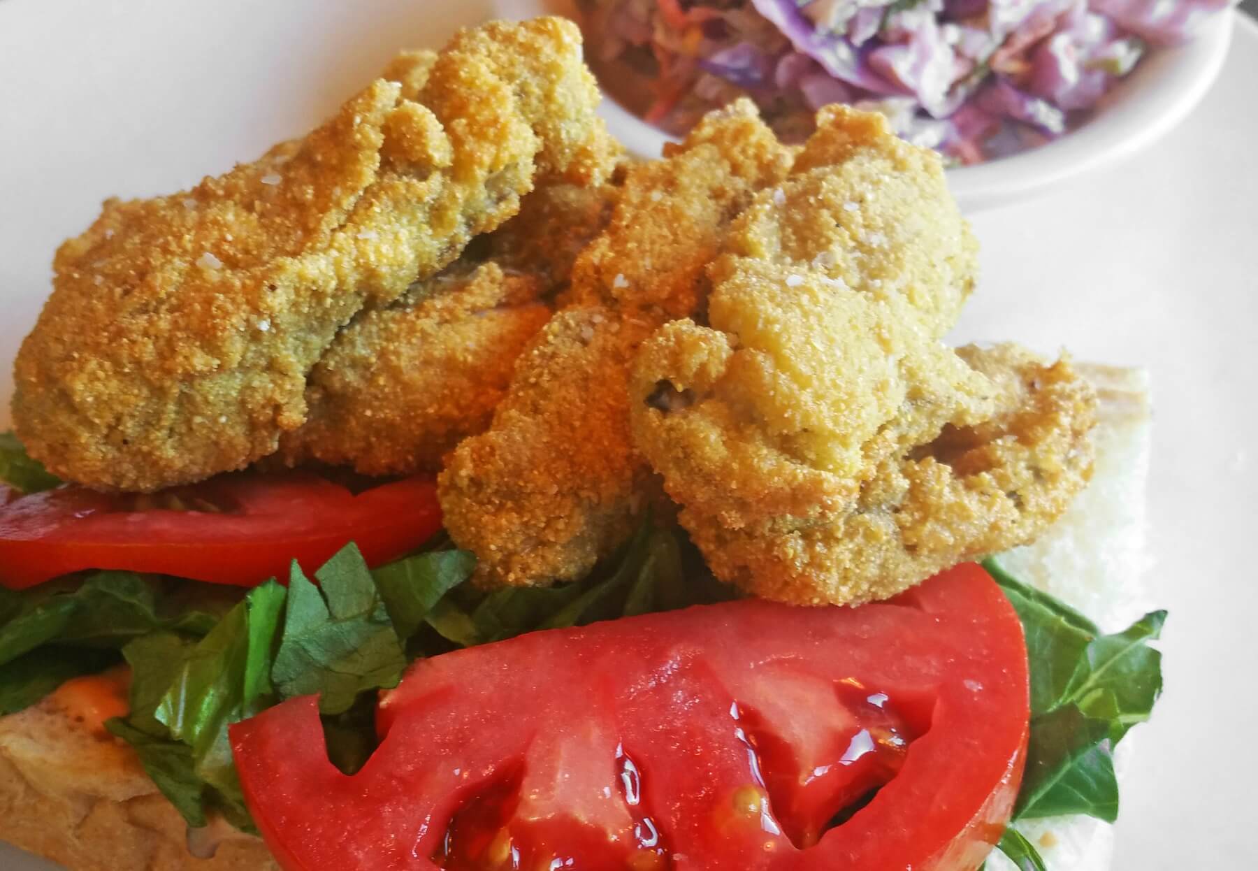 This fried oyster Bayou La Batre-style po boy is served on authentic New Orleans Gambino's bread with lettuce, tomato and a tasty remoulade.