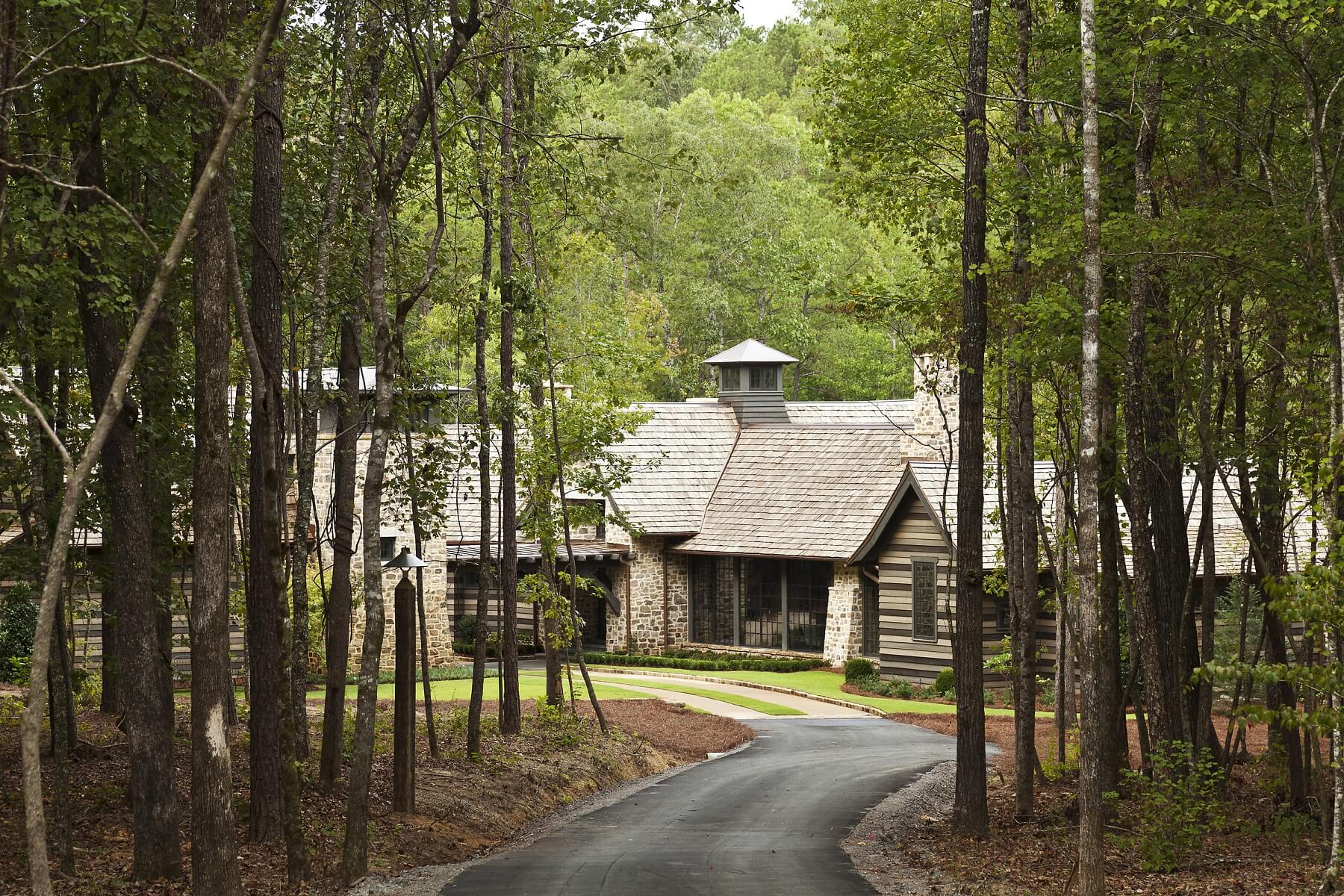 A long driveway winds toward the home, which is tucked among the trees.