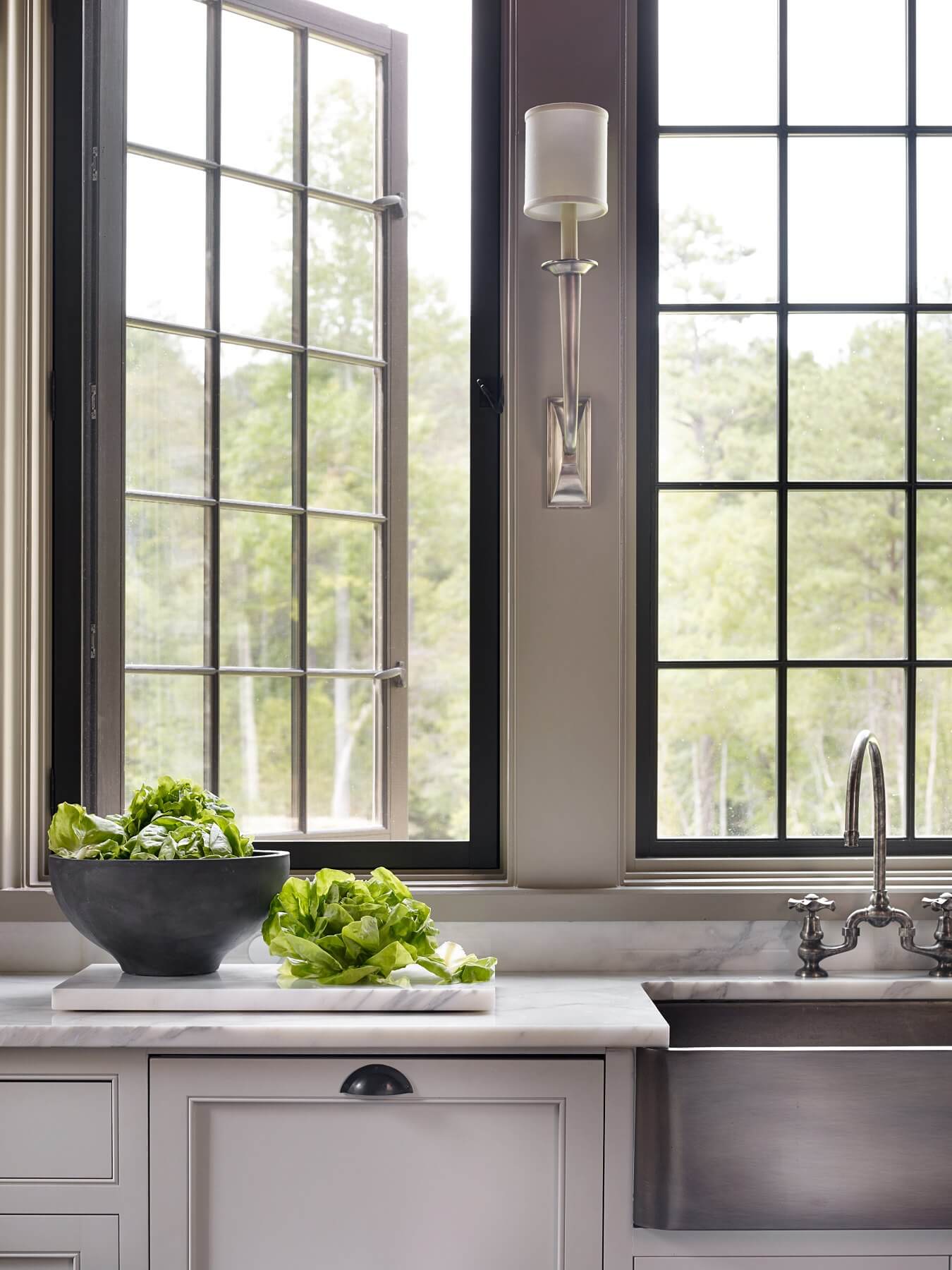 Beautiful hardware and countertops gleam in the natural light. Large windows invite fresh air to usher gentle breezes through the kitchen. 