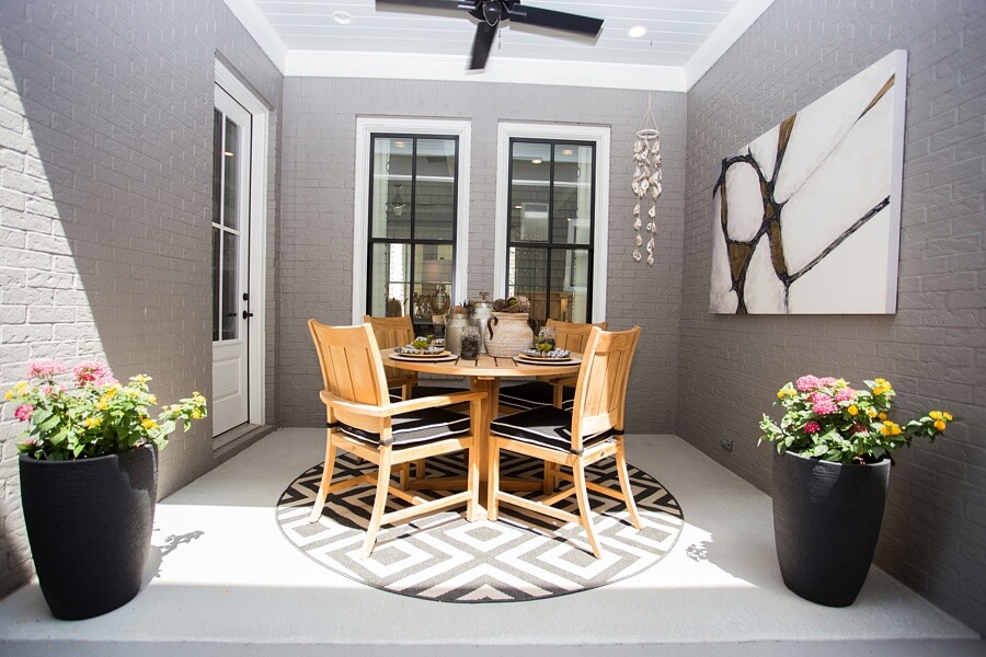 This covered outdoor space just outside the home's dining area makes for a cozy, intimate space for morning coffee al fresco dinners. The large abstract artwork adds a touch of drama and the light wood table and chairs invite warm conversations. 