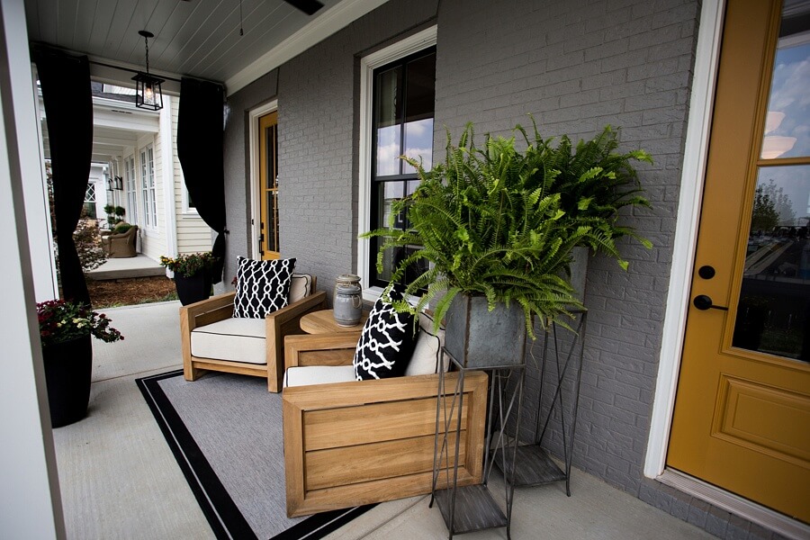 Weathered metals, earthy ceramics, graphic prints and rustic but sophisticated outdoor seating combine for a comfortable gathering spot by this home's inviting entrance.