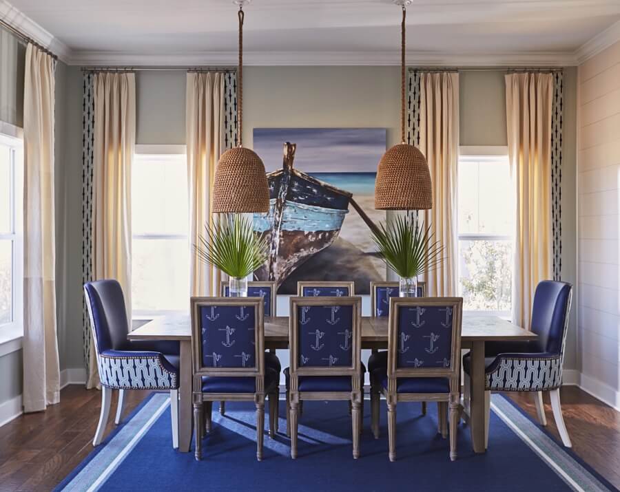 A painting by NC artist https://storeyellis.com/ distinguishes the dining room. Kristin used indigo blue faux-leather to cover the chairs, with accent fabrics to liven things up.  Basket pendants by https://www.palecek.com/ add a casual vibe to the room.