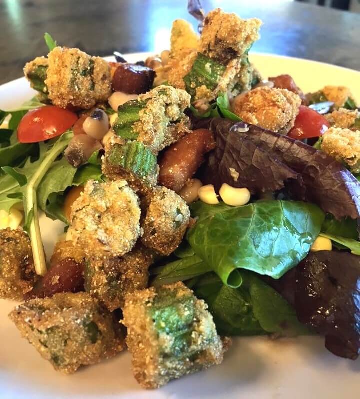 This farmers' market salad features fresh greens, cherry tomatoes, back-eyed peas, corn and fried okra for the perfect balance of fresh vegetable and sinful fried crunch!
