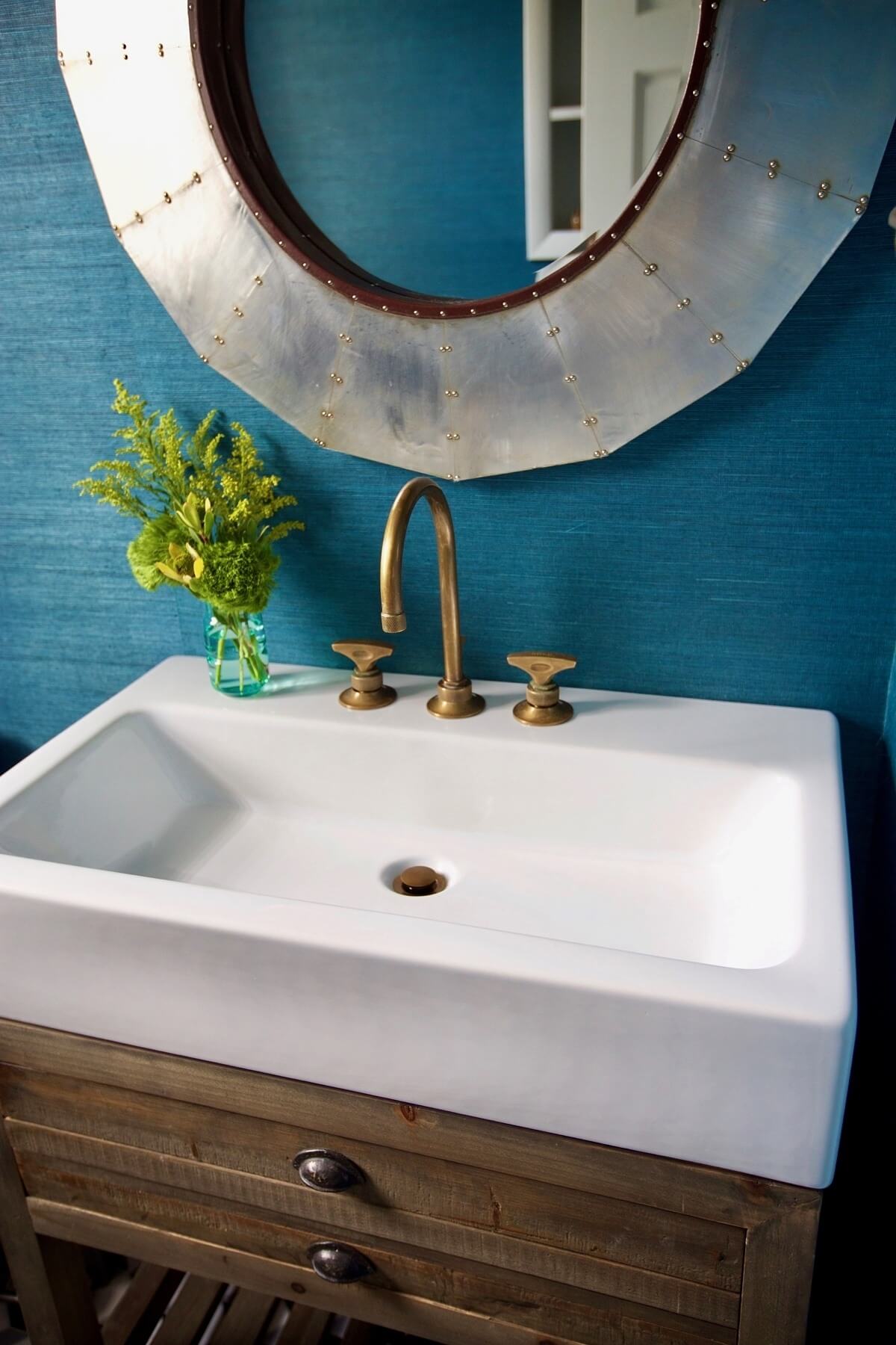 "The navy grasscloth wallpaper made the bathroom," says Marianne. And paired with the warm-industrial sink and metal-and-leather-wrapped mirror, it is simply stunning. Image: Beth Hontzas