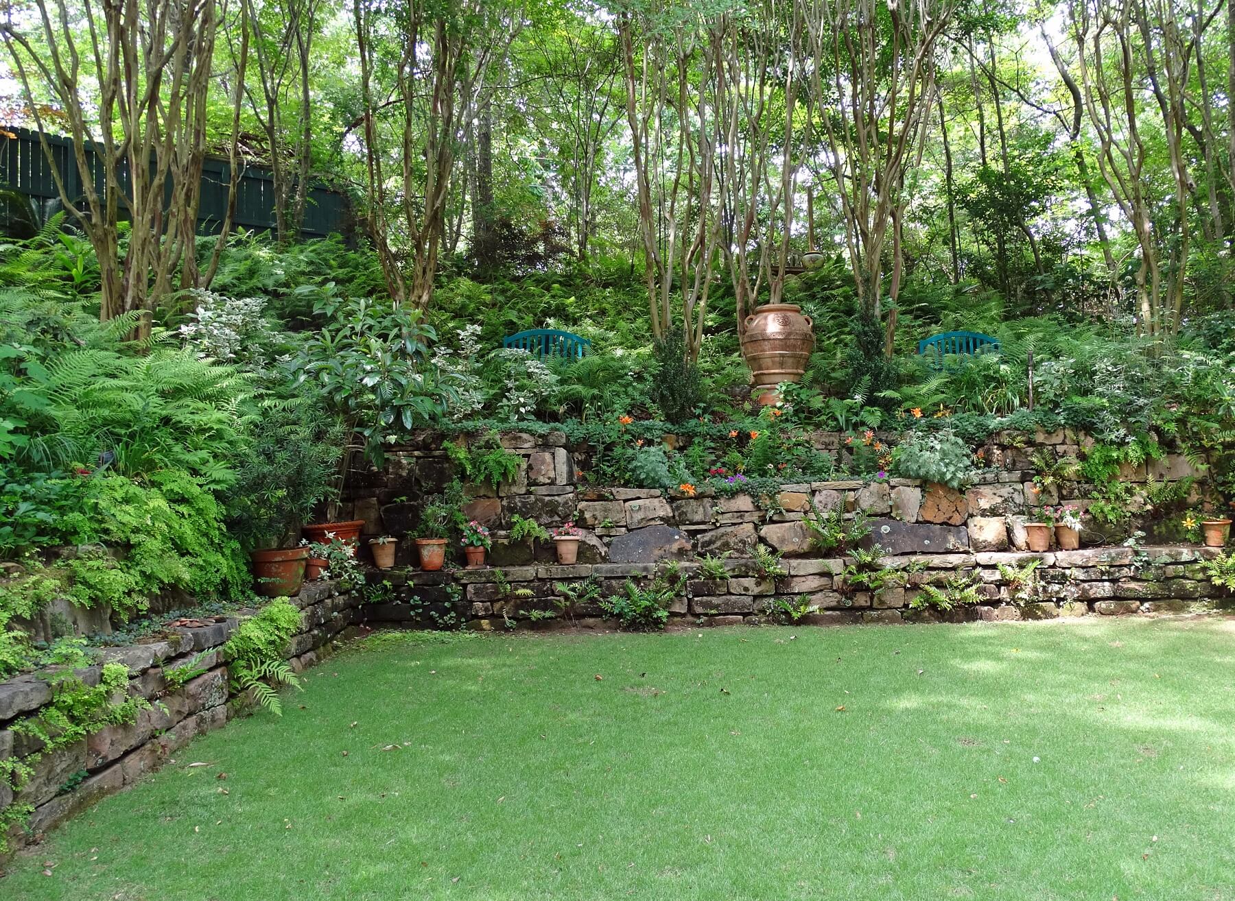 Ferns seem to crawl out of the stone, reaching toward this well manicured court.