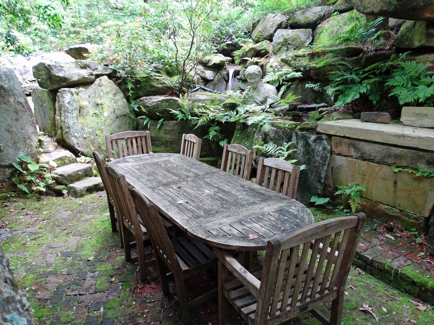 Enclosed among gigantic stones, this mossy brick patio is the perfect setting for a magical evening dinner under the stars or an afternoon lunch under the canopy of trees above.