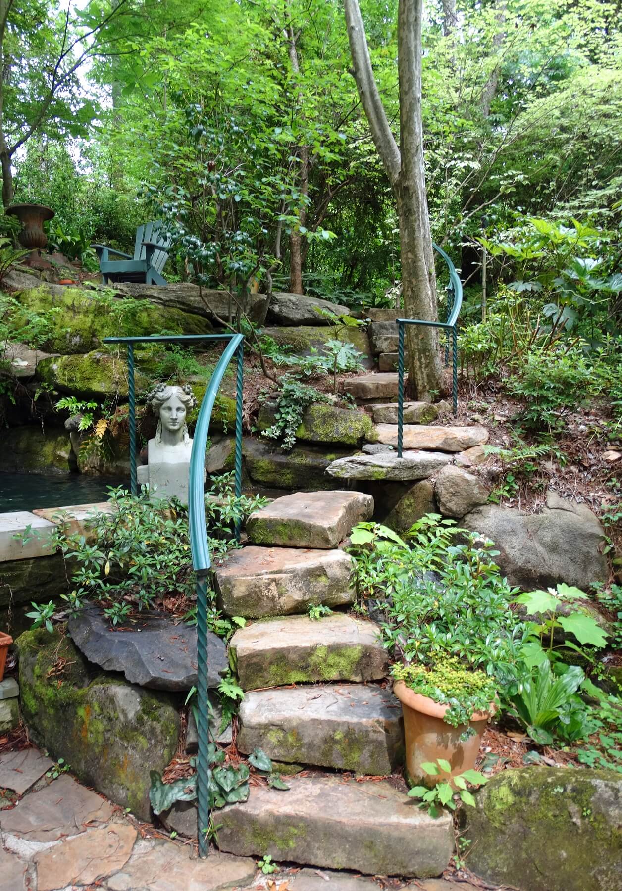 A curving stone staircase winds around the waterfall and pool.