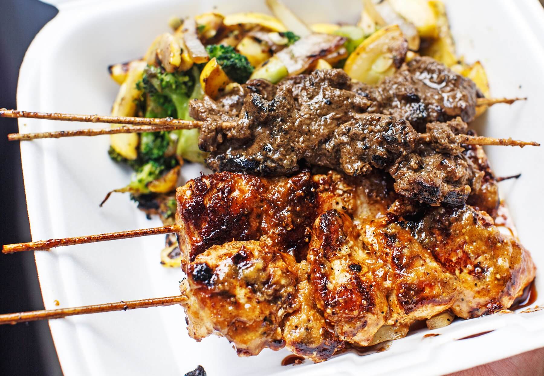 A Stickem platter with grilled shrimp and steak skewers, grilled veggies, and rice
