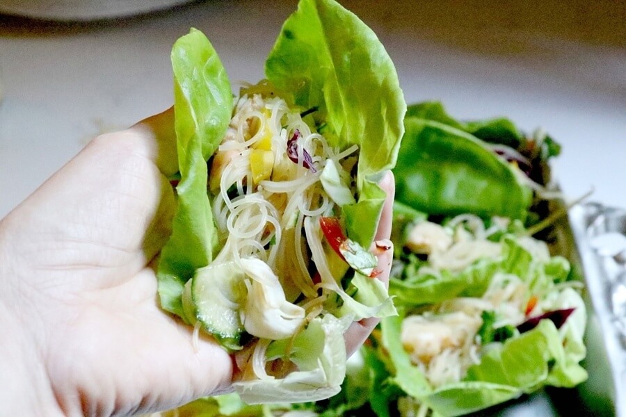 Person holding a lettuce wrap with spring roll salad.