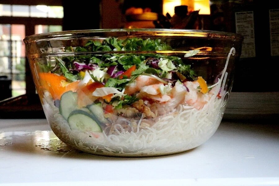 Salad ingredients in a glass bowl before being mixed together.