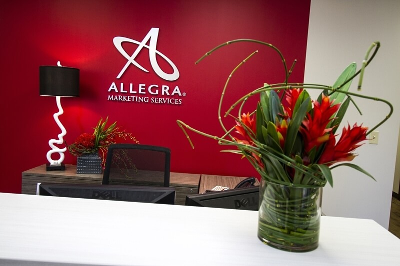 The lipstick red of Allegra's new business cards was used on the feature wall for a pop of color against their new logo.