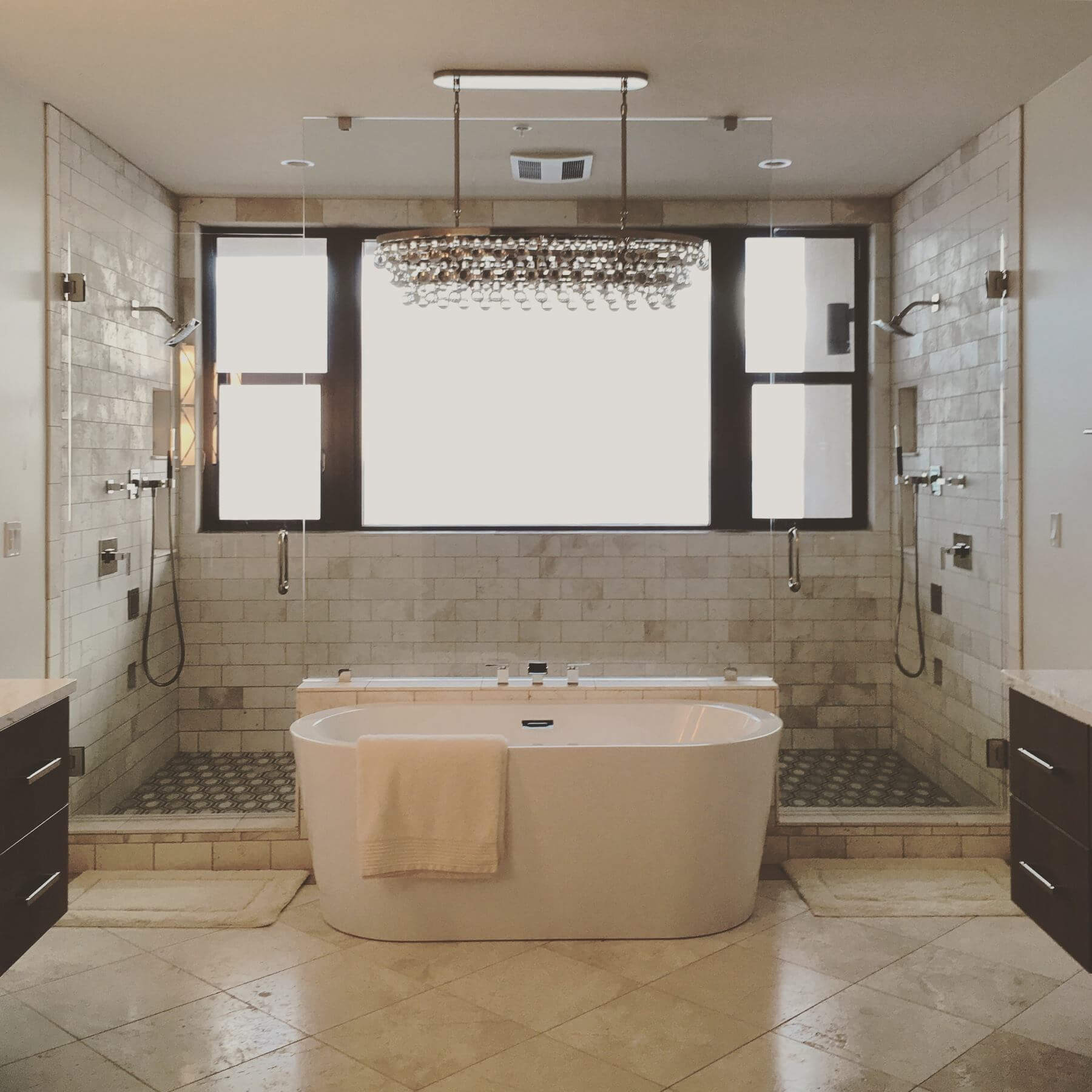 After: The entire bathroom was reconfigured, including relocating the tub to the center of the bathroom area, installing new floating vanity cabinets, and a large walk-in shower.
