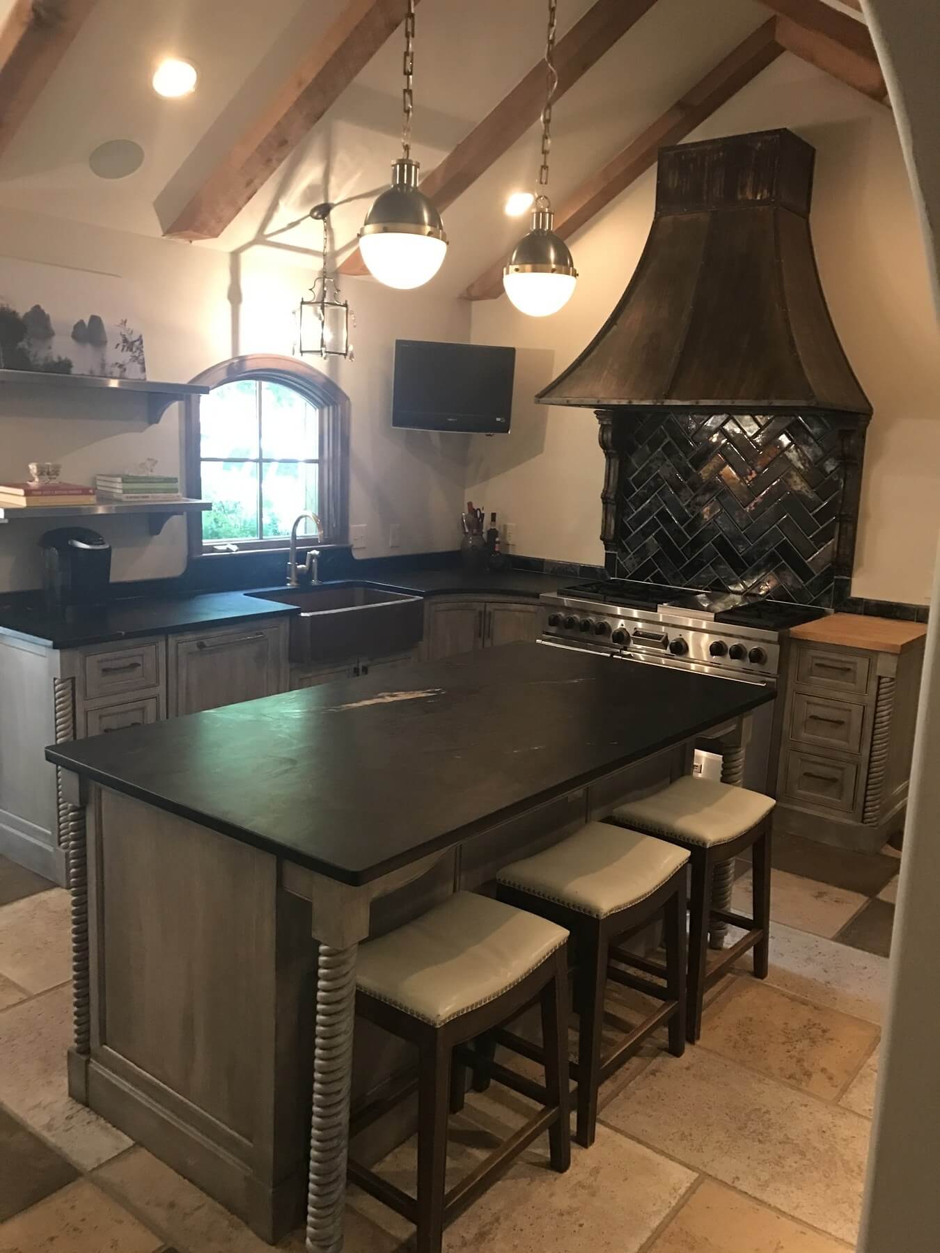 After: With a modern black-white-and-gray color palette and rough-hewn beams, this renovated kitchen exudes timeless charm with modern accents.