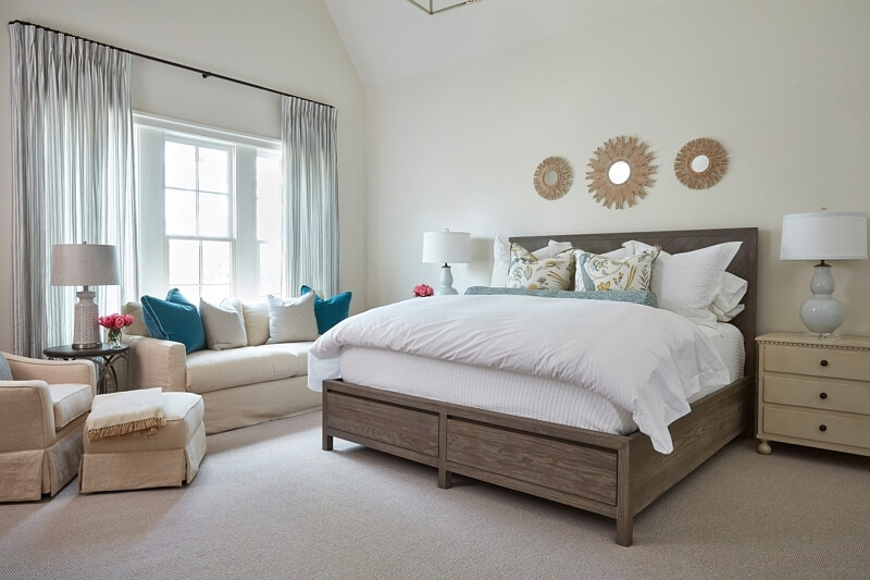 A guest suite includes a comfortable seating area and a trio of mirrors above the bed.