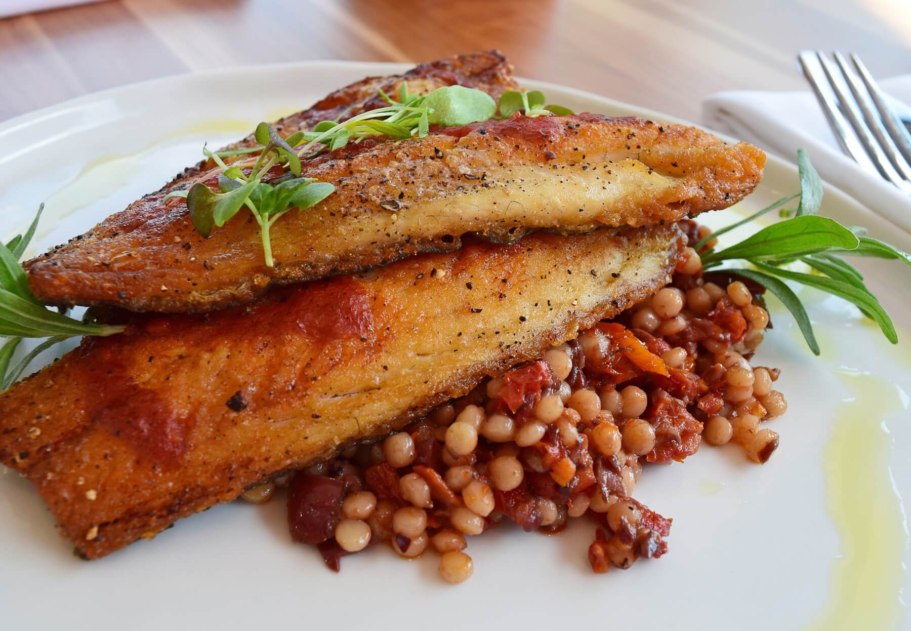The Striped Bass served over a bed of Israeli couscous with sun-dried tomatoes, olives and a sweet pepper purée is delicious option for lunch or dinner. novel