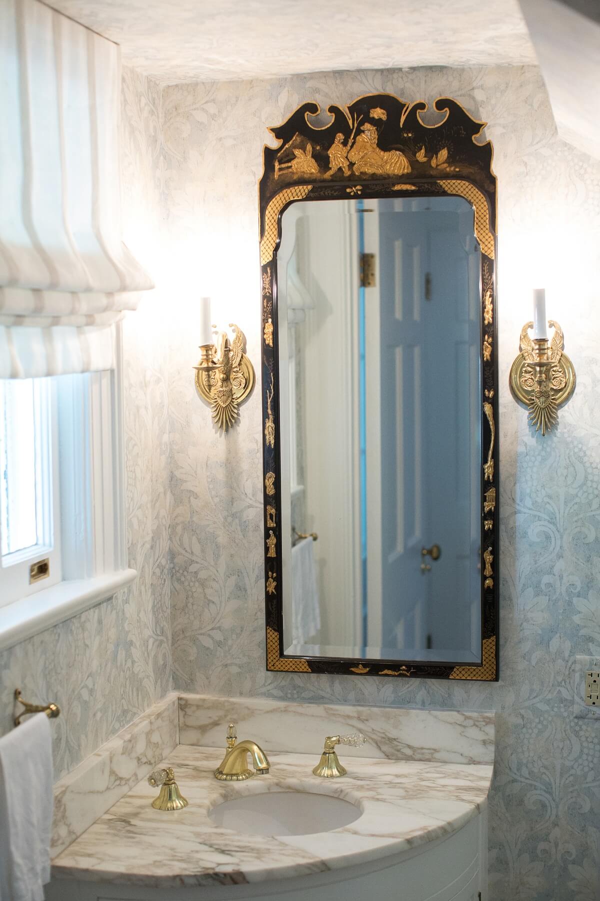 This black antique mirror with gilded accents is given the spotlight, when set against this soft pastel wallpaper. This black antique mirror with gilded accents is given the spotlight, when set against this soft pastel wallpaper.