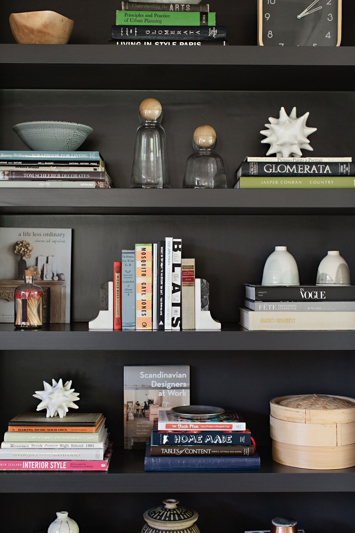 Design Tips for Styling Bookshelves: "If a bookcase isn’t singing, it probably doesn’t have enough books. Secondly, mix in accessories that have a variety of shapes, colors, and textures to add interest and give it a more personal touch. In this case, the black backdrop really makes the shapes shine," says Fran. "Keep stacks of books clean with small shapely objects at the top of your stacks and intermittently through the books. If you want a modern look, give the books and accessories room to breathe." Scandinavian-style family home