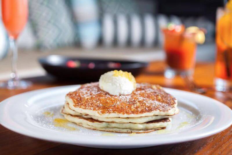 Plate of pancakes with butter and powdered sugar.
