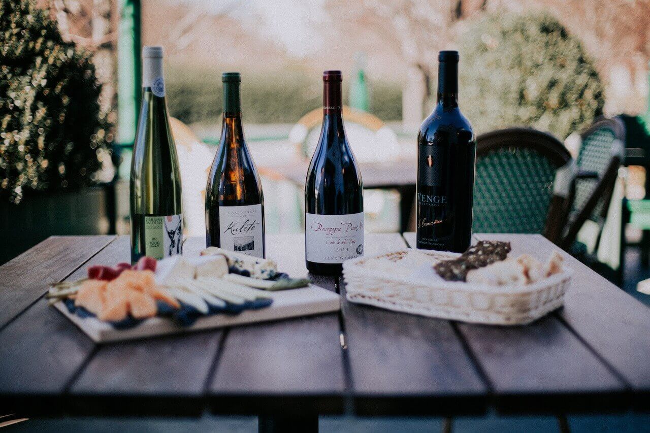 Bottles of wine and cheeseboards on an outdoor picnic table