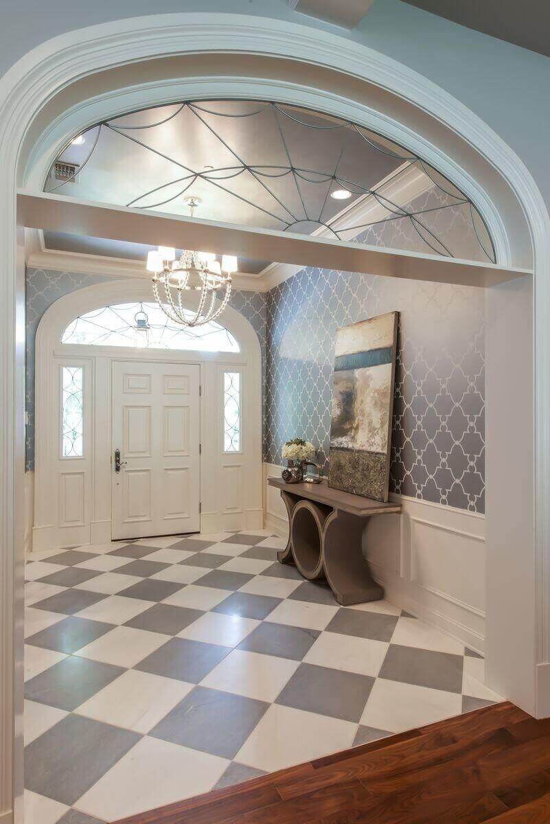 The entryway welcomes guests with a custom front door featuring heavy casing, transitional sidelights and a web-inspired Palladian transom window on top.