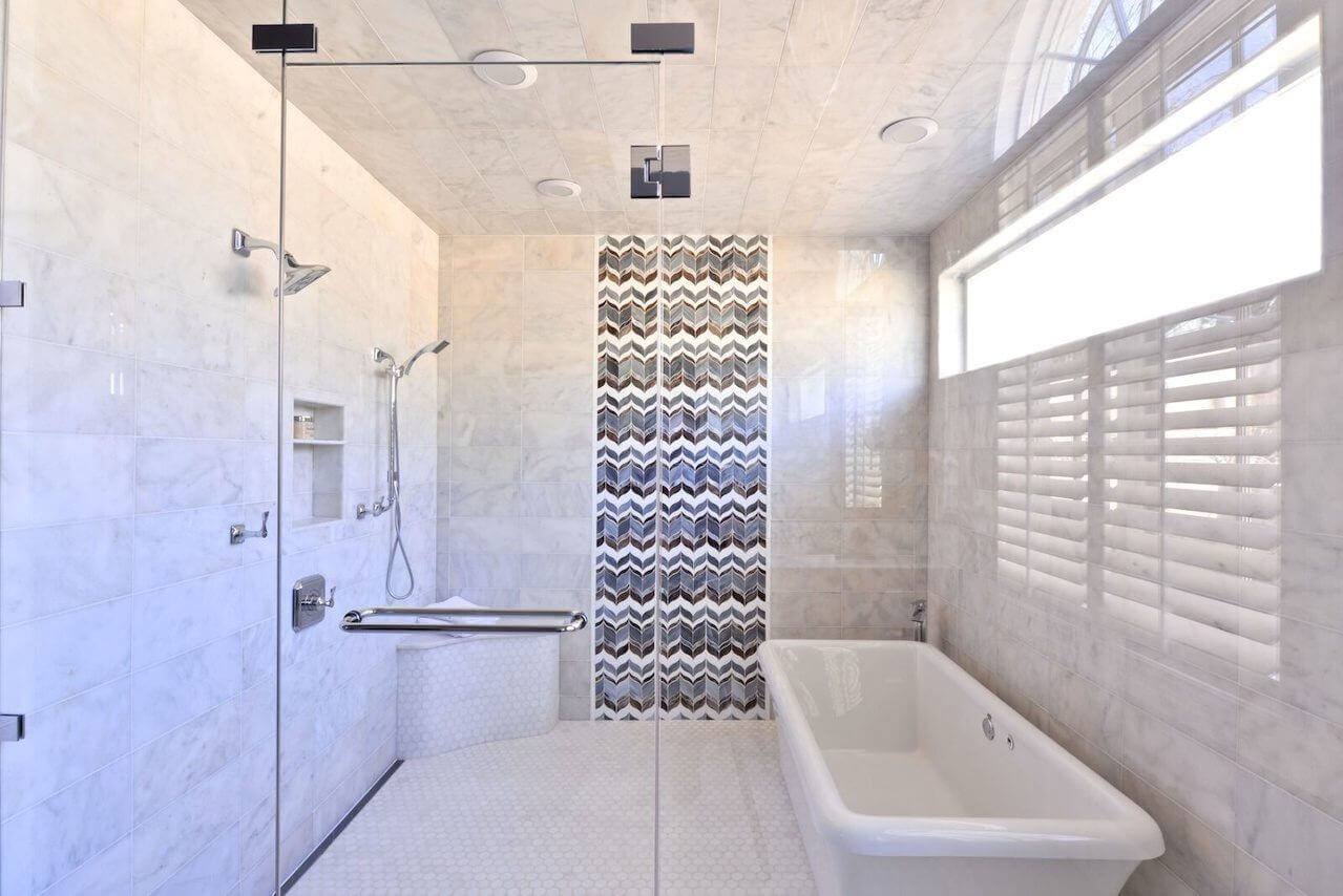 Chevron-patterned tiles are a striking focal point in the wet room, with its free-standing tub and multiple shower heads.