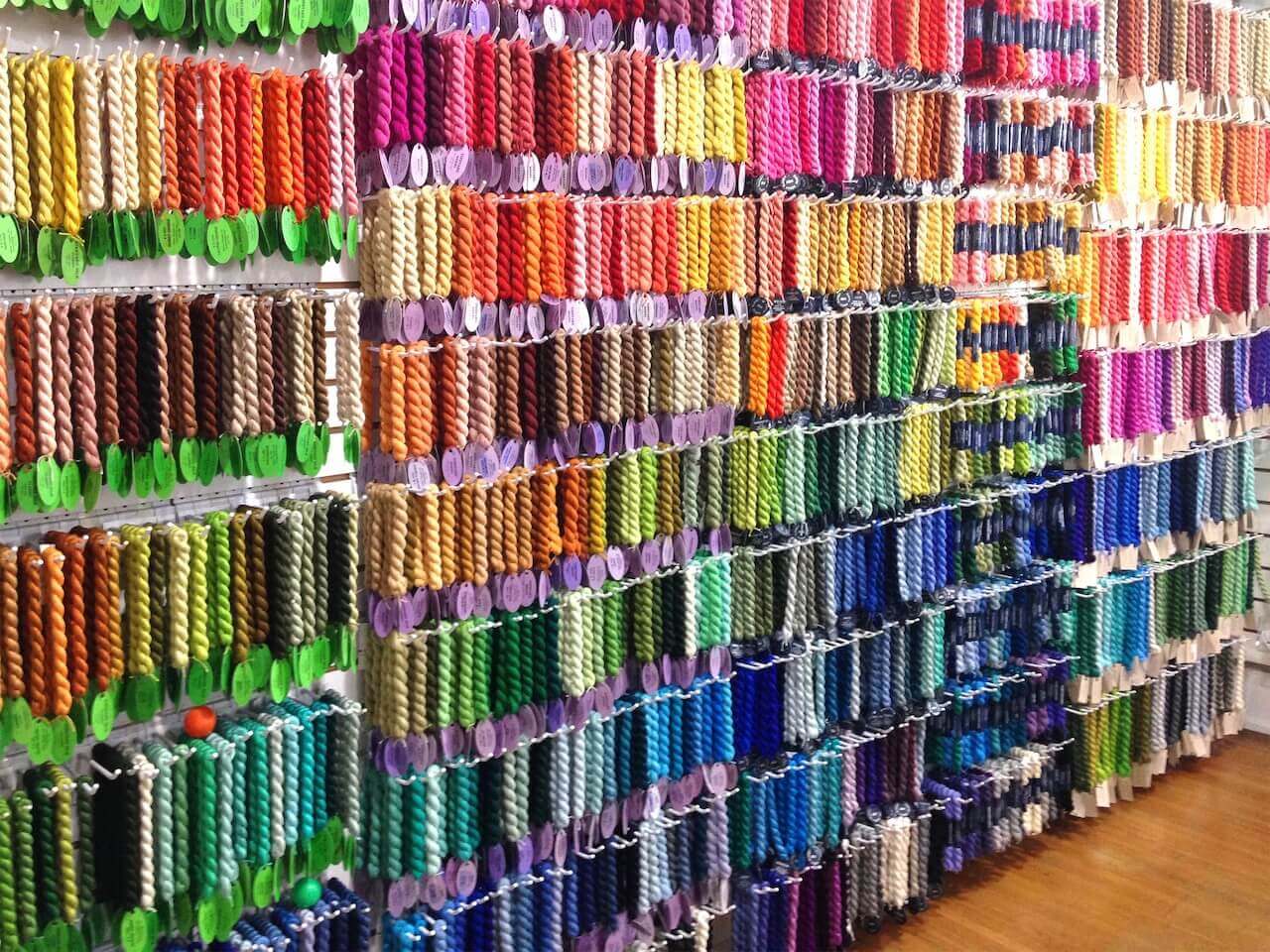 Rows and rows of brightly colored thread lines the walls of this needlepoint haven. Rows and rows of brightly colored thread lines the walls of this needlepoint haven.