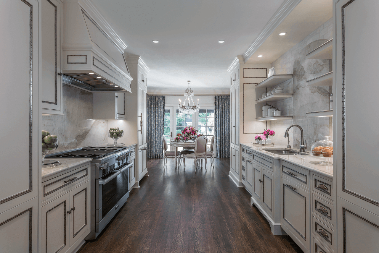 The simple elegance of the white cabinetry and marble counter tops in Ami’s kitchen contrasts exquisitely with the dark-brown, hard-wood flooring. At the far end of the kitchen’s gallery sits her well-appointed tabletop rife with magnificent elements for entertaining friends for brunch.