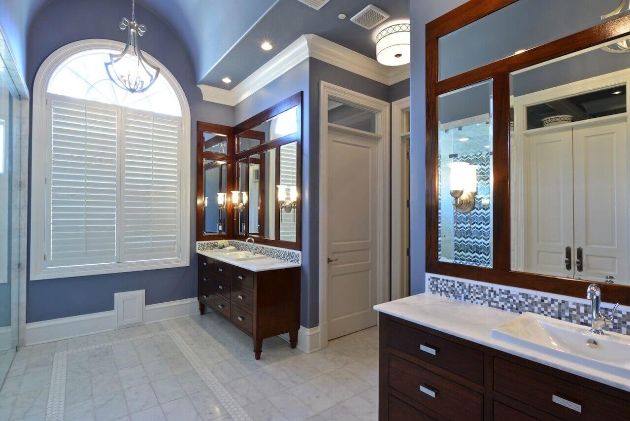 A dark wood stain on the vanities contributes to the rich look, with a mosaic tile backsplash as an added detail.
