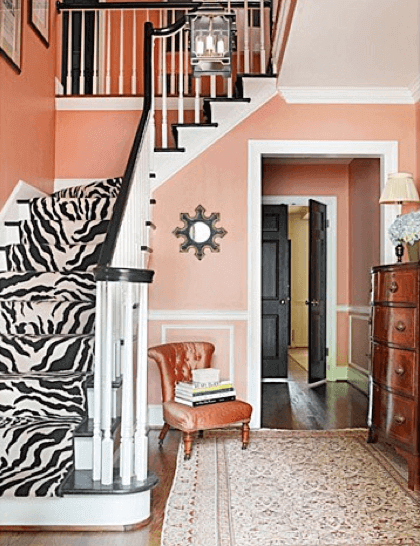 A peachy custom paint color provides the base for this rich foyer, accented with a Stark zebra rug runner and Oriental rug on the floor.