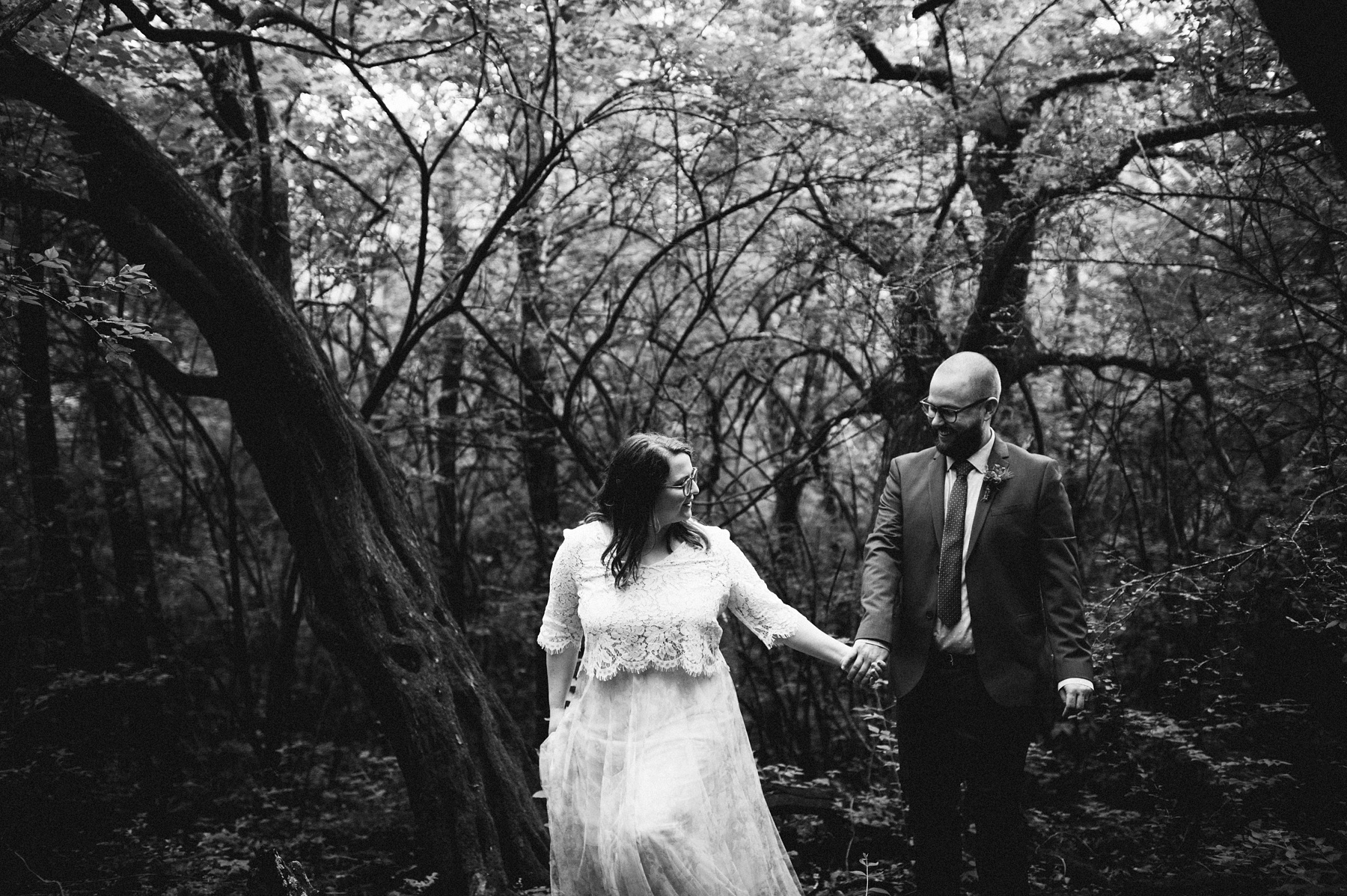 Jessica Hendrickson and Brian Sample walk hand in hand through the woods surrounding the treehouse in this image that truly looks like it was pulled straight from a fairytale! treehouse wedding