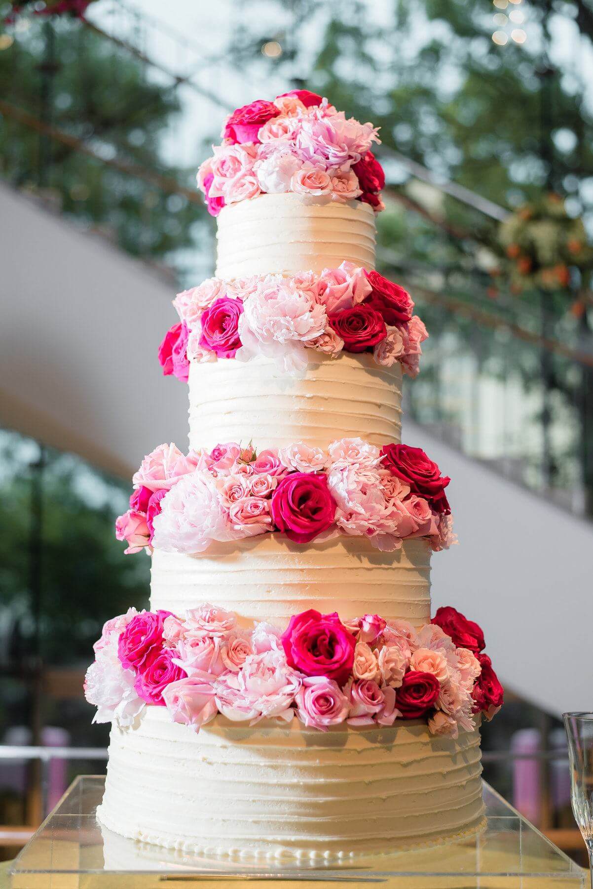 Ashley has a bit of a sweet tooth and says that cake is very important to her. (We can relate!) So, she knew that her wedding cake simply had to come from Olexa’s. Classic meets modern in this simple four-tier cake adorned with roses in shades of pink, seemingly floating above the table on a lucite cake stand. 