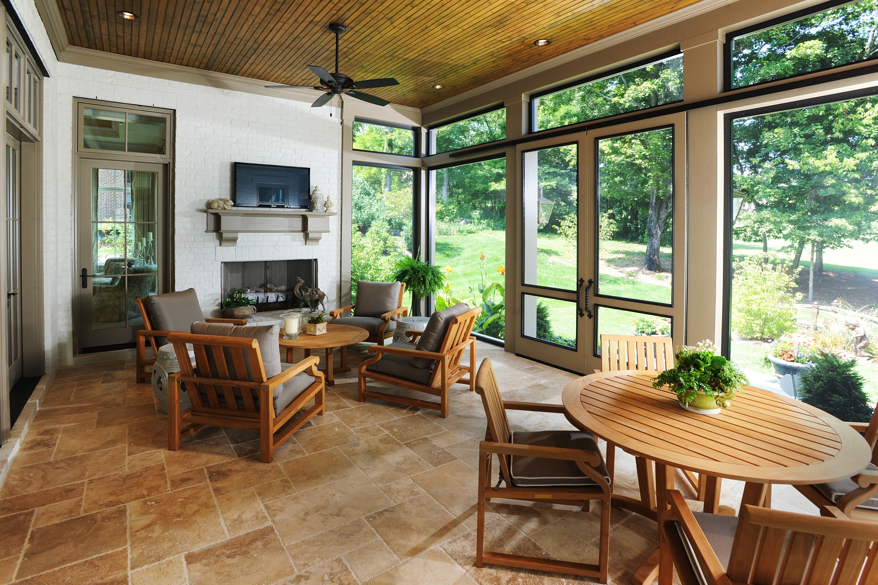 Sometimes a permanent screen, rather than a retractable screen, is the right choice, as is the case with this spacious, enclosed year-round porch. Warm colors and teak furnishings create a welcoming vibe for lounging and dining. Double doors use a barn door-style mechanism. “They allow for a very efficient traffic flow on and off the back porch,” Brandon says.