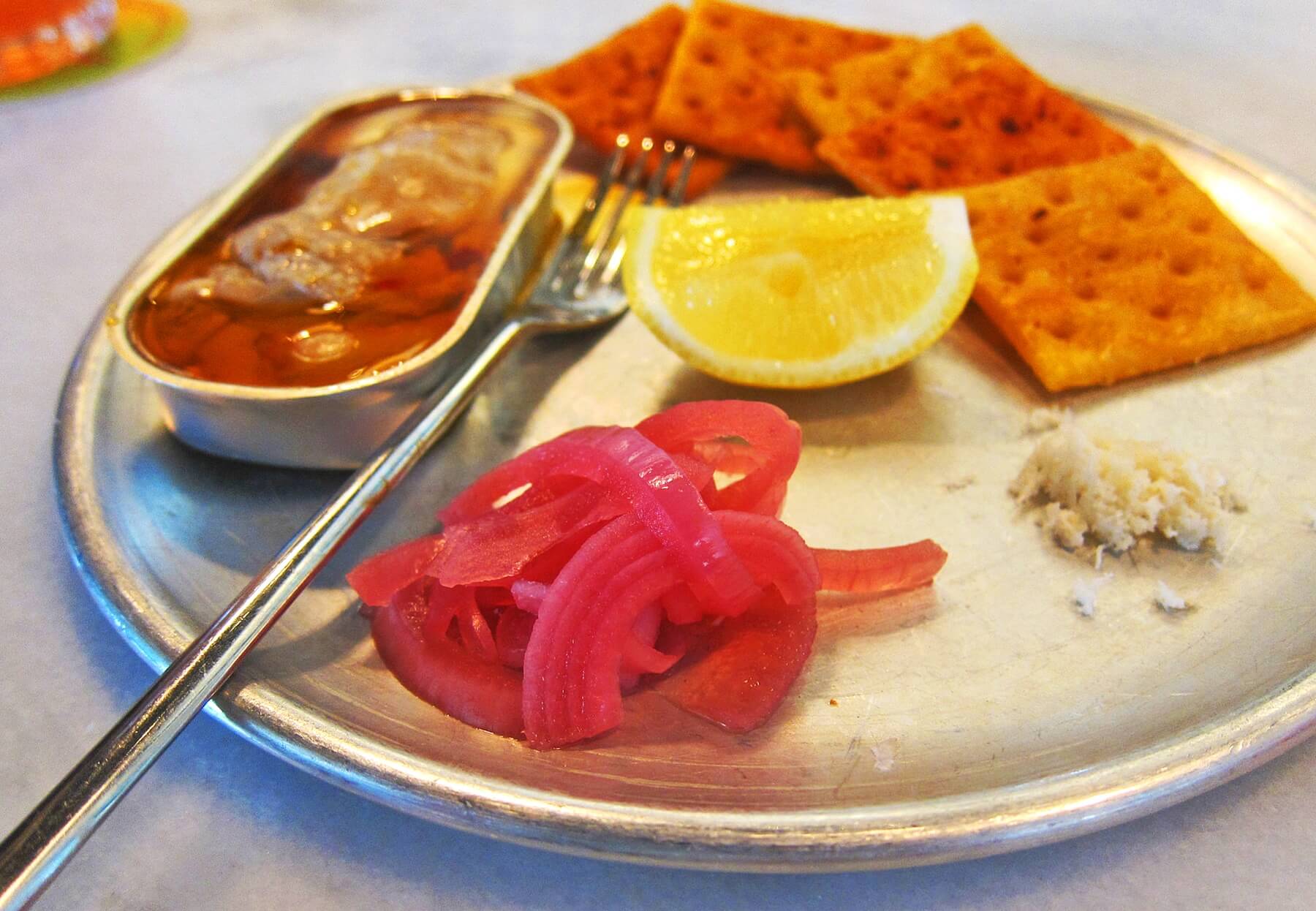 Smoked oysters served in a precious little tin with pickled onions and fancy crackers