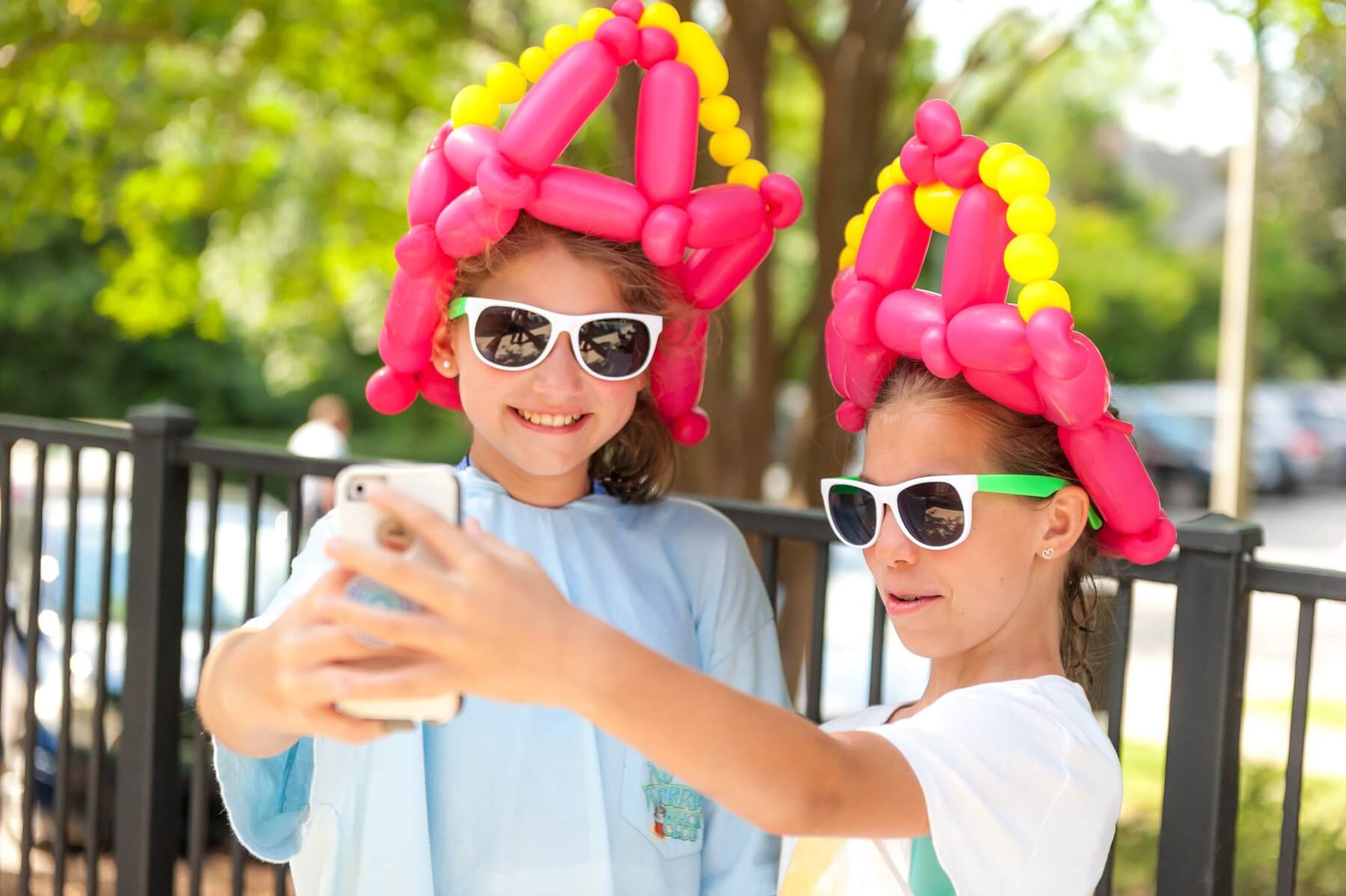 Girls pose in balloon hats at a fun neighborhood event. Liberty Park