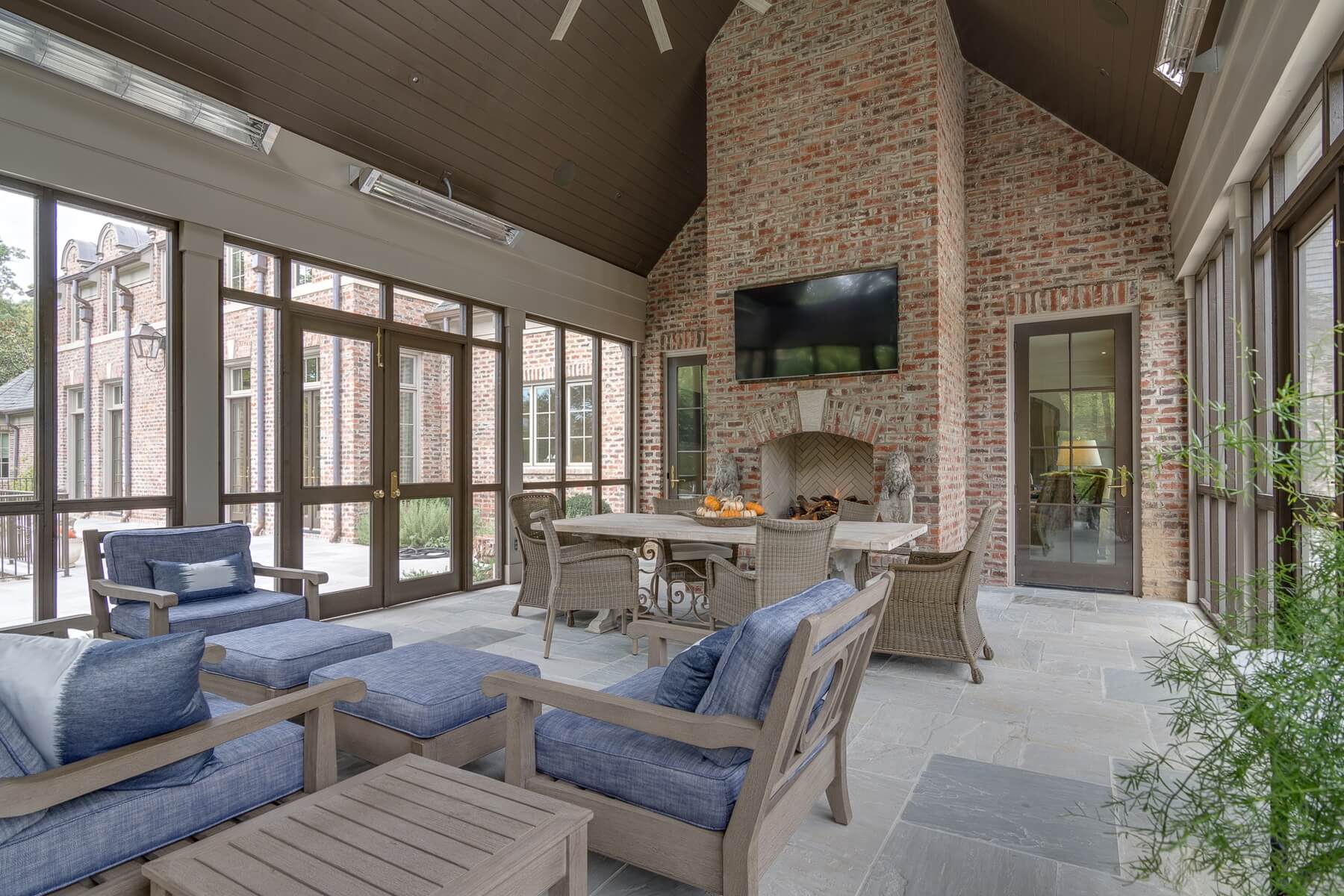 This spacious screened porch features a fireplace installed by Bishop Hearth & Home that adds warmth and coziness to the fully equipped dining space.