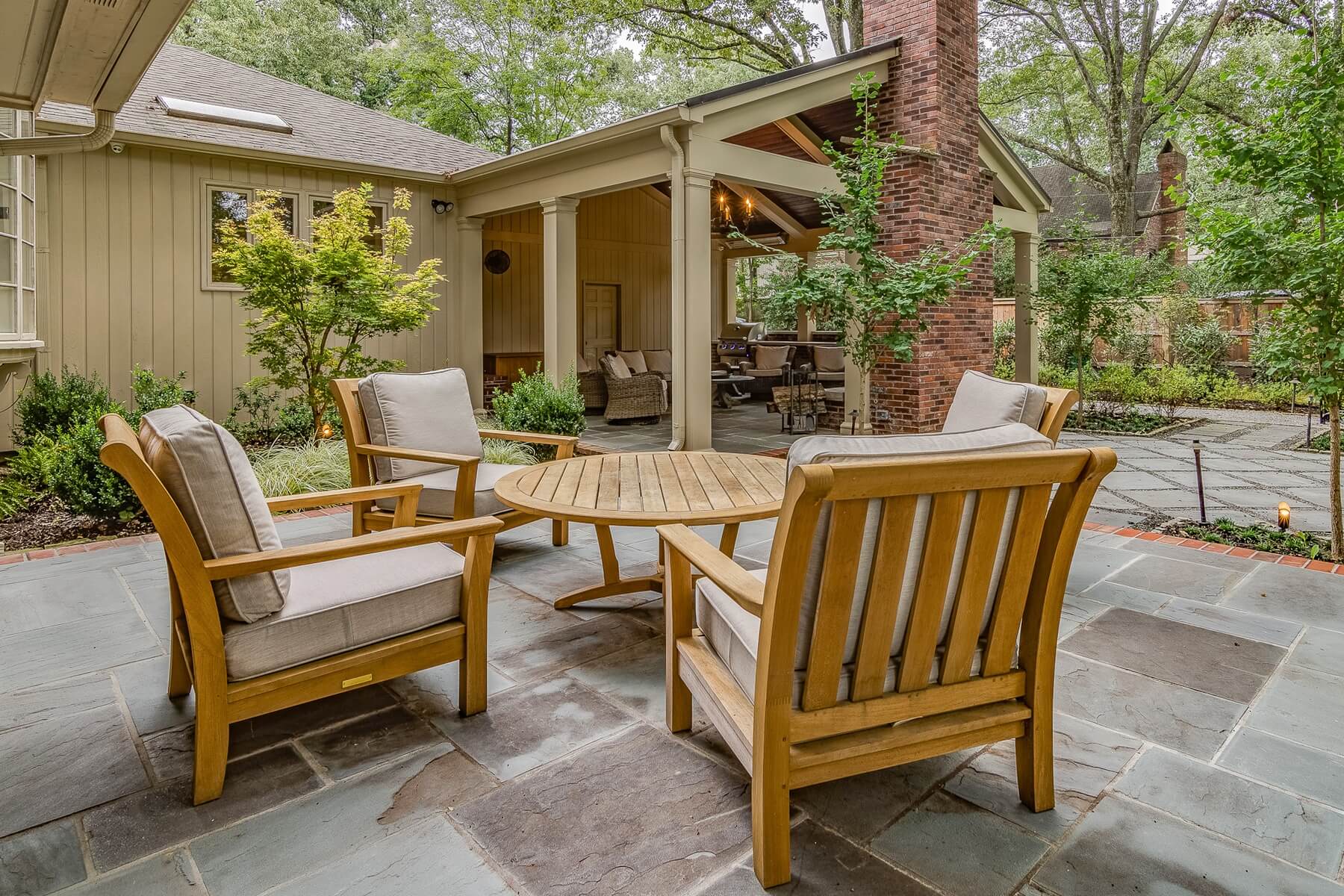 Bishop sells teak furnishings in a variety of styles to suit a variety of outdoor rooms. Teak stands up well in uncovered spaces, like this slate patio.