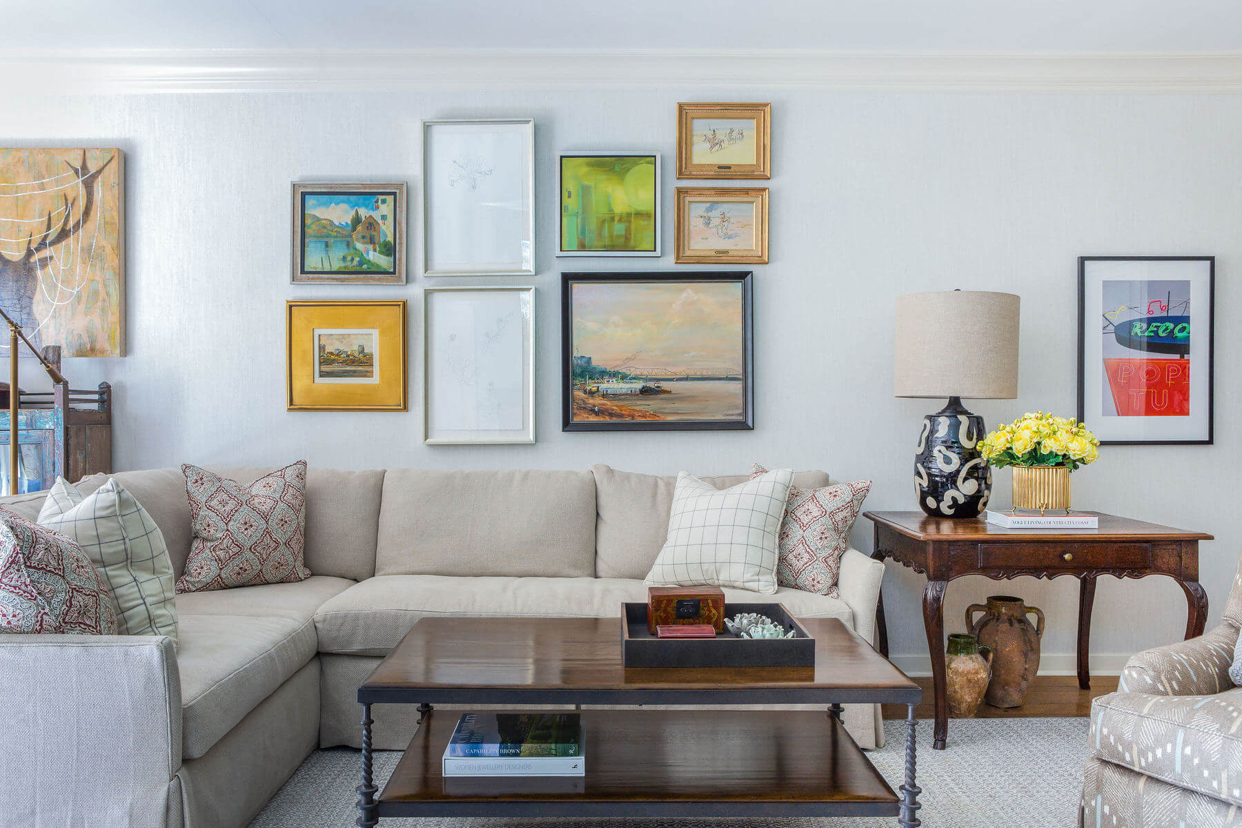 In this cozy den, a large sectional sofa lends itself well to a family-friendly hangout space, while an eclectic mix of artwork on the gallery wall creates a vivid focal point. The two pencil drawings at the heart of the arrangement are by artist Carlyle Wolfe. In this cozy den, a large sectional sofa lends itself well to a family-friendly hangout space, while an eclectic mix of artwork on the gallery wall creates a vivid focal point. The two pencil drawings at the heart of the arrangement are by artist Carlyle Wolfe.