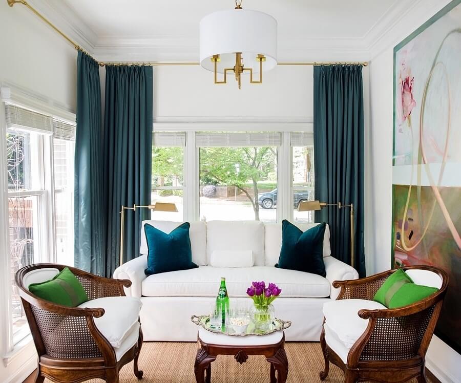 The mostly white palette of this Raleigh condo allows the turquoise window treatments in the sunroom to stand out. “We decided to splurge on custom window treatments in silk to dress up the space, and because silk captures the depths of colors like no other fabric,” says designer Katie O’Neal. white color palette