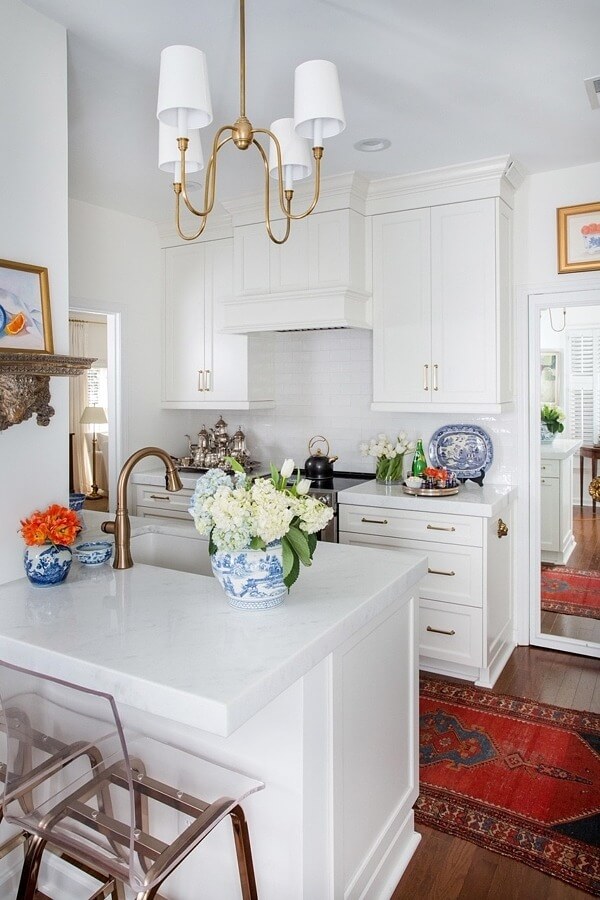 This kitchen may be on the tiny side, but it’s packed with upgrades, starting with new cabinetry that spans to the ceiling. Marble countertops are a substantial four inches thick, and the new range hood is also bigger (yet understated). Gold accents and a bold red Oriental runner make this white kitchen anything but plain. kitchen design