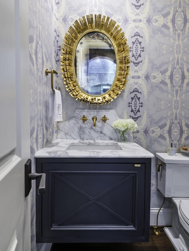 The same goes for this beauty of a half-bath with a bold gold mirror and lavender wallpaper. Castle Homes