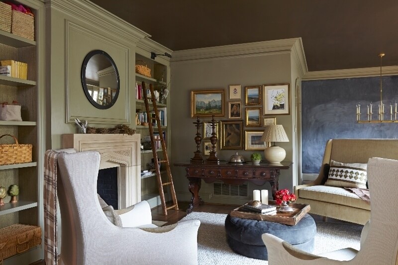 A gorgeous antique side table anchors a collection of art, while modern furniture is gathered loosely toward the stunning stone fireplace. living room- Melanie Pounds